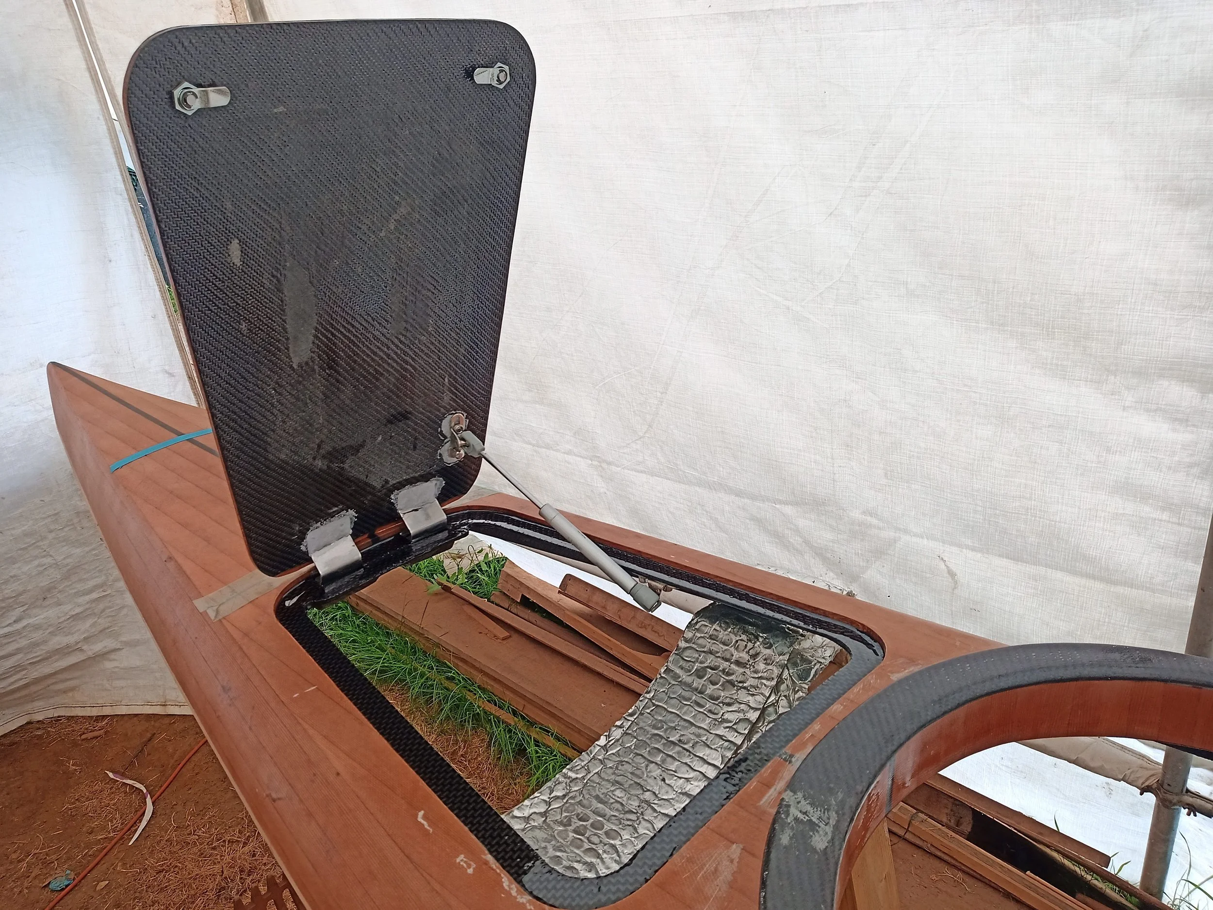 A gas strut holds the hatch open. Stainless hardware was chosen for corrosion resistance. Hinges were bonded to the hatch with epoxy to enable a strong, low profile joint.