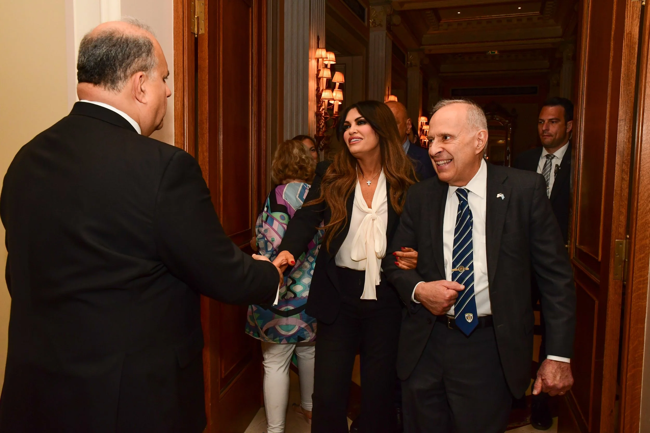 AHI Chairman James H. Lagos, Esq., escorts Ambassador Kimberly Guilfoyle at the 21st Annual AHI Athens Awards Dinner as AHI President Nick Larigakis welcomes her to the event 
