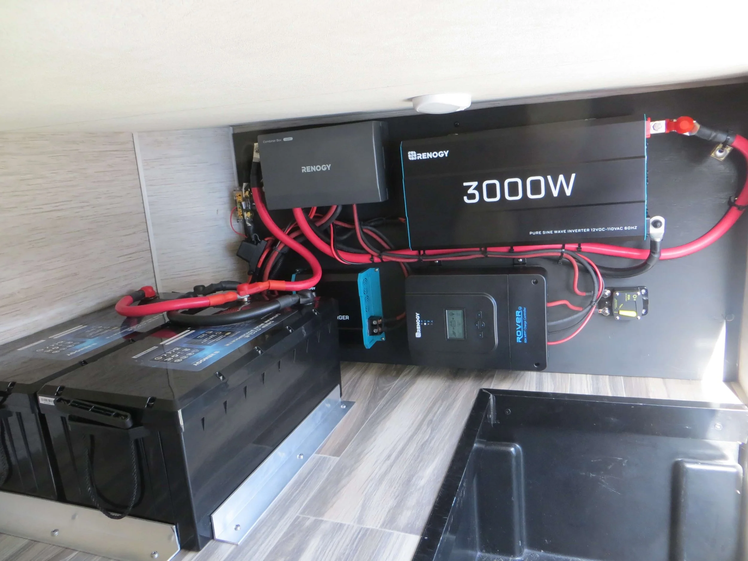 A solar power system setup with a large black inverter labeled 3000W, a black battery,Example of RV Solar Install near San Diego. Lithium Battery, DC/DC Converter, LiFePO4, Inverter, install on RV near San Diego, CA.