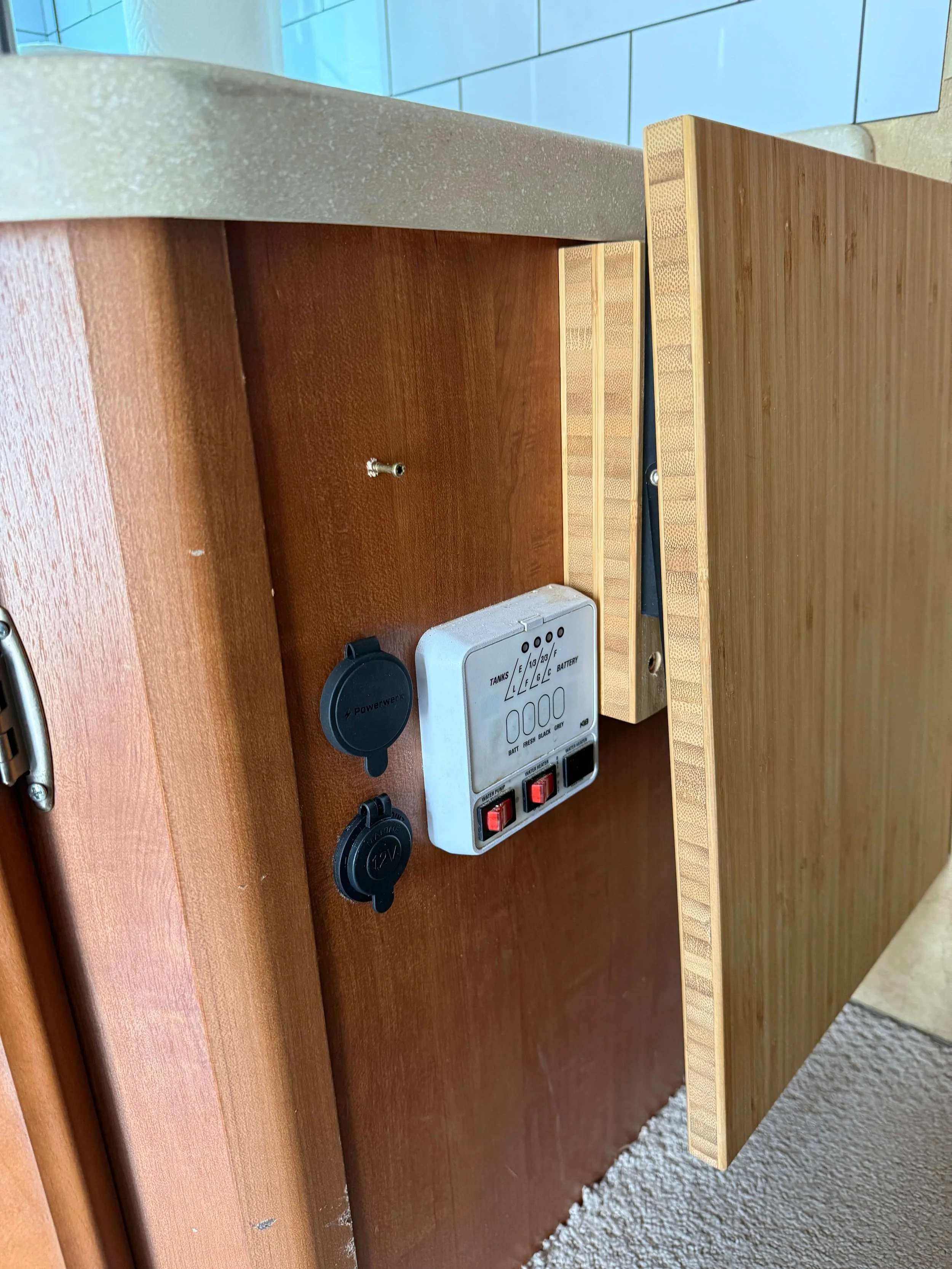 Close-up of a wooden panel with electrical outlets and a control panel, next to a wood and laminate surface.Example of RV Solar Install near San Diego.  Lithium Battery, DC/DC Converter, LiFePO4, Inverter, install on RV near San Diego, CA.