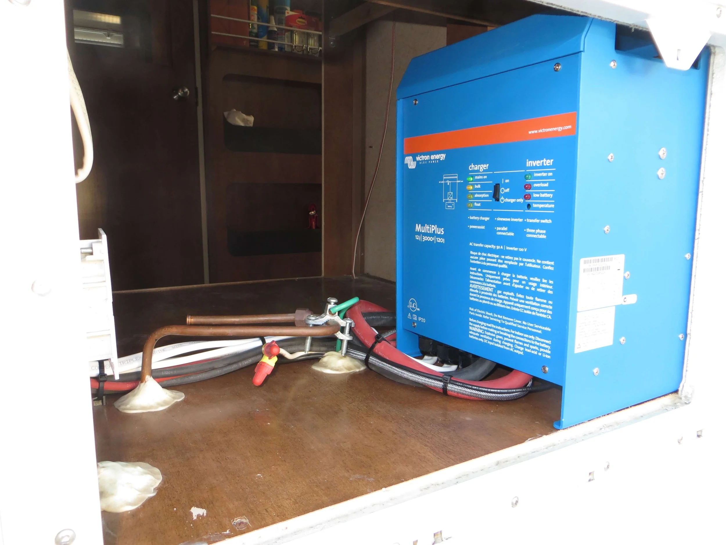 Blue Victron Energy inverter and charger unit installed inside a compartment  example of RV Solar Install near San Diego.  Lithium Battery, DC/DC Converter, LiFePO4, Inverter, install on RV near San Diego, CA.