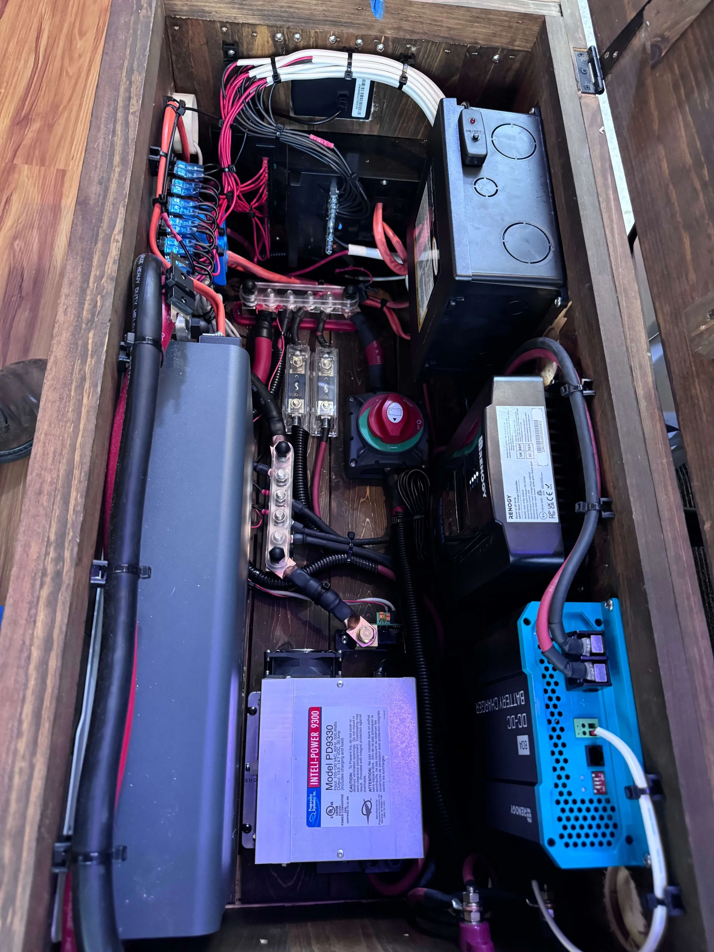 Interior view of an electrical or electronic control box with various wires, connectors, and components such as power supplies, batteries, and circuit breakers. Example of RV Solar Install near San Diego.  Lithium Battery, DC/DC Converter, LiFePO4, I