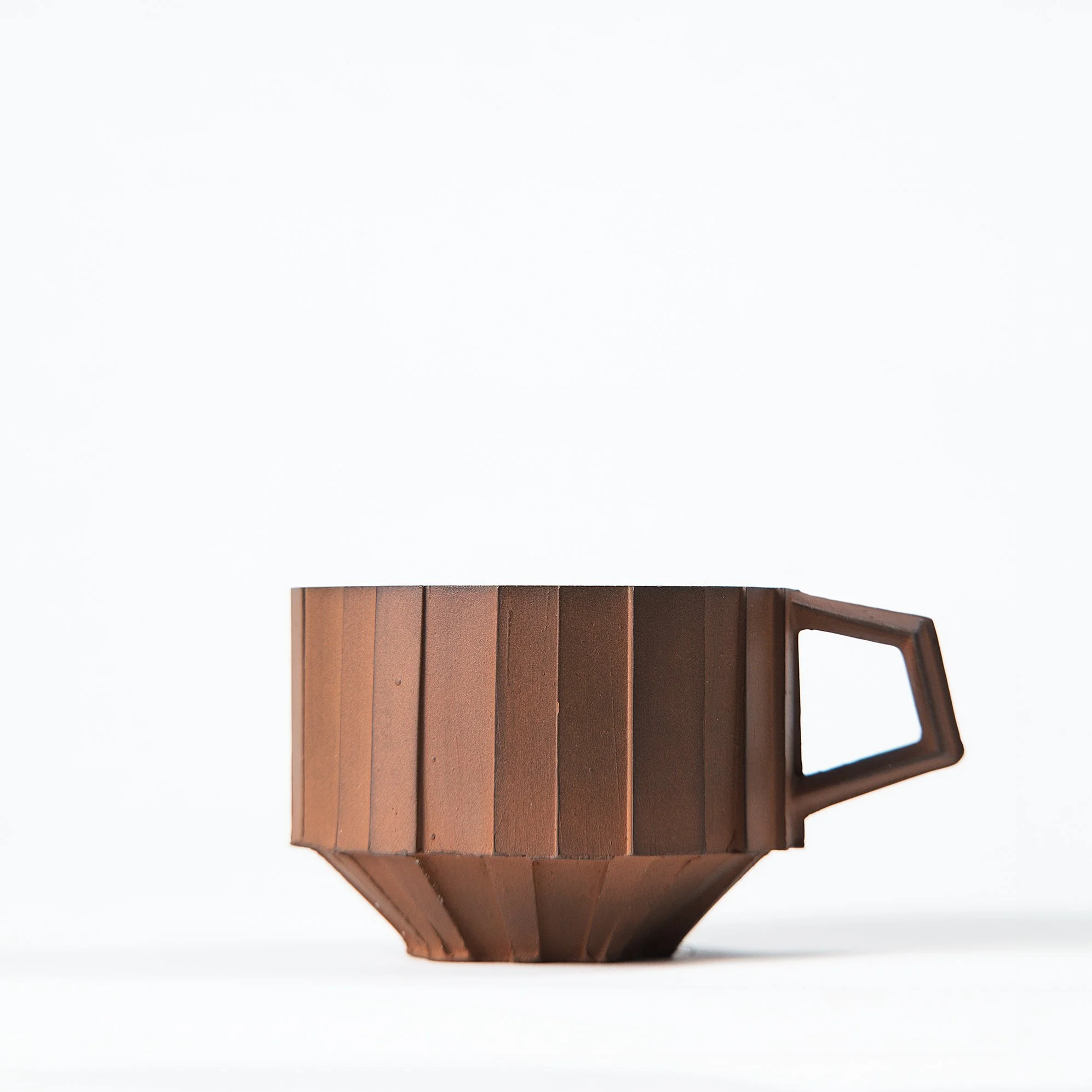 Handmade faceted ceramic cup with unglazed red stoneware exterior and off-white glazed interior, by Lea & Nicolas
