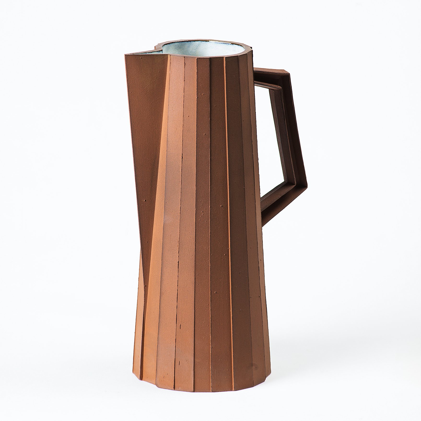 Handmade faceted ceramic pitcher with unglazed red stoneware exterior and off-white glazed interior, by Lea & Nicolas