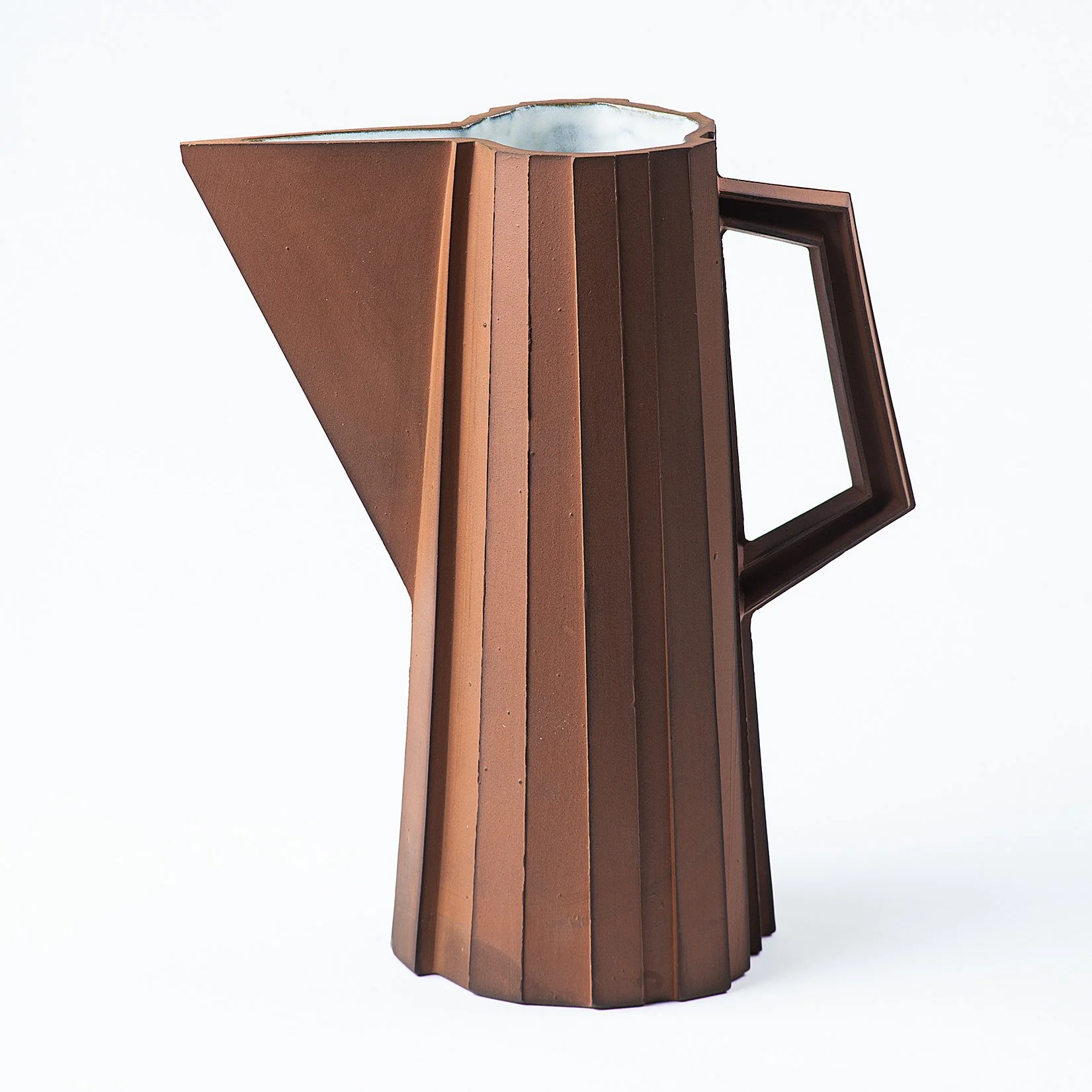 Handmade faceted ceramic pitcher with unglazed red stoneware exterior and off-white glazed interior, by Lea & Nicolas