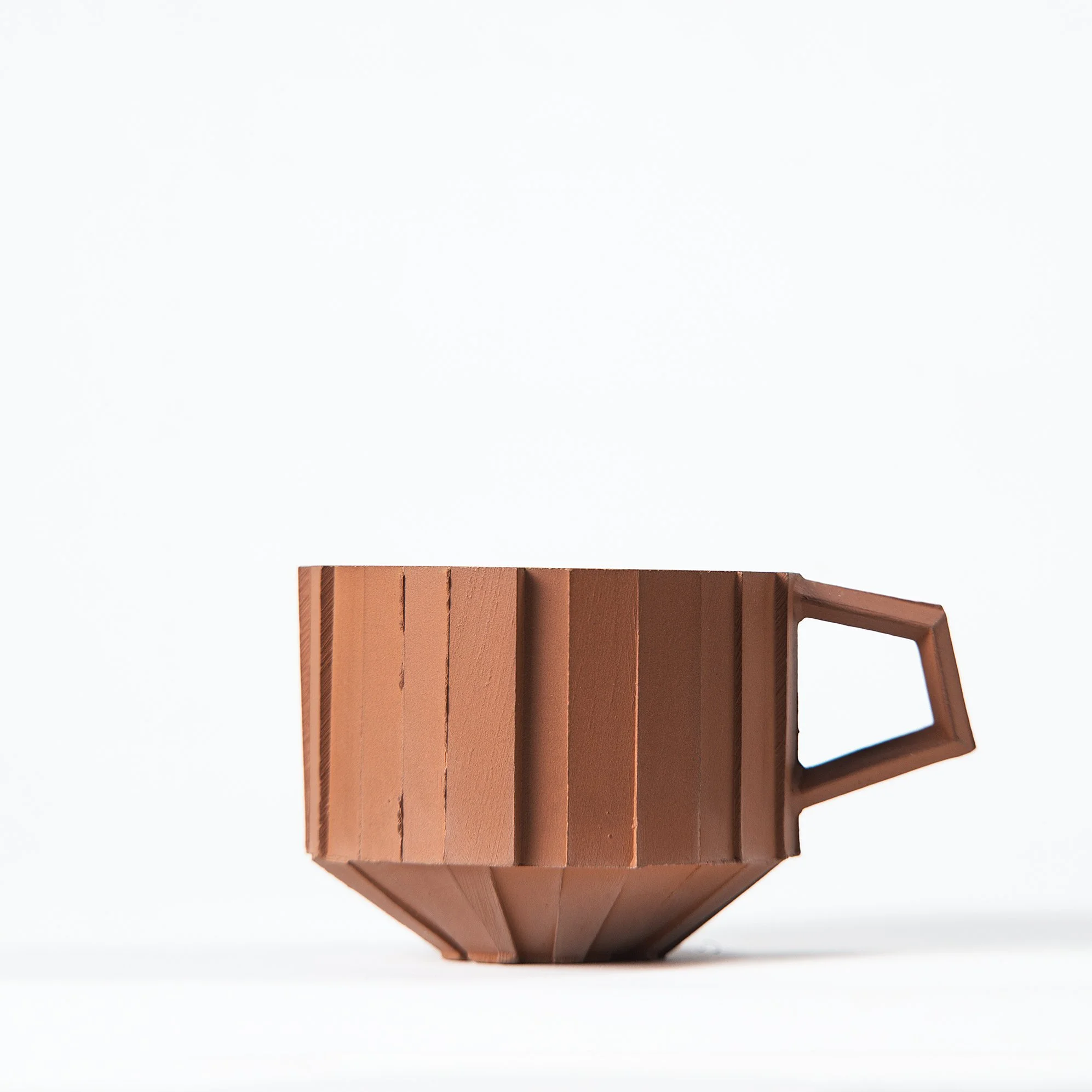 Handmade faceted ceramic cup with unglazed red stoneware exterior and off-white glazed interior, by Lea & Nicolas