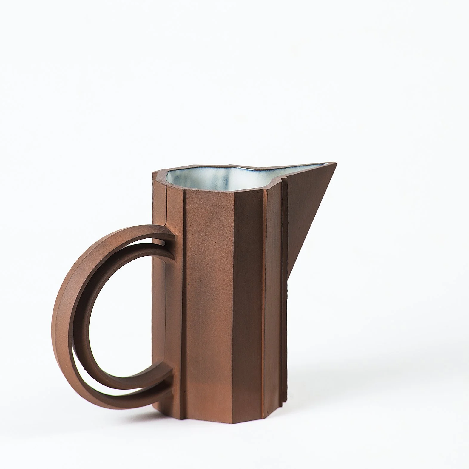 Handmade faceted ceramic pitcher with unglazed red stoneware exterior and off-white glazed interior, by Lea & Nicolas