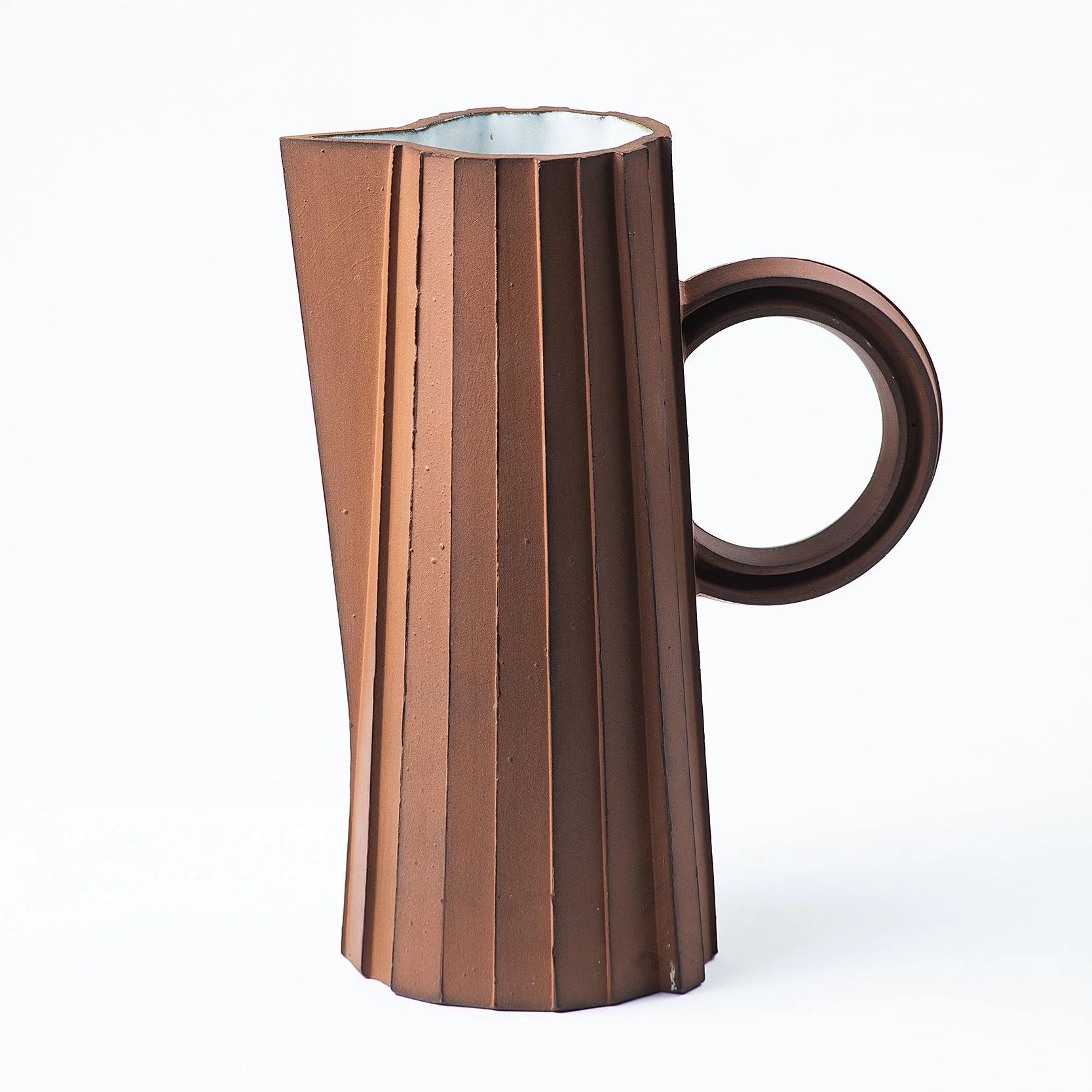 Handmade faceted ceramic pitcher with unglazed red stoneware exterior and off-white glazed interior, by Lea & Nicolas