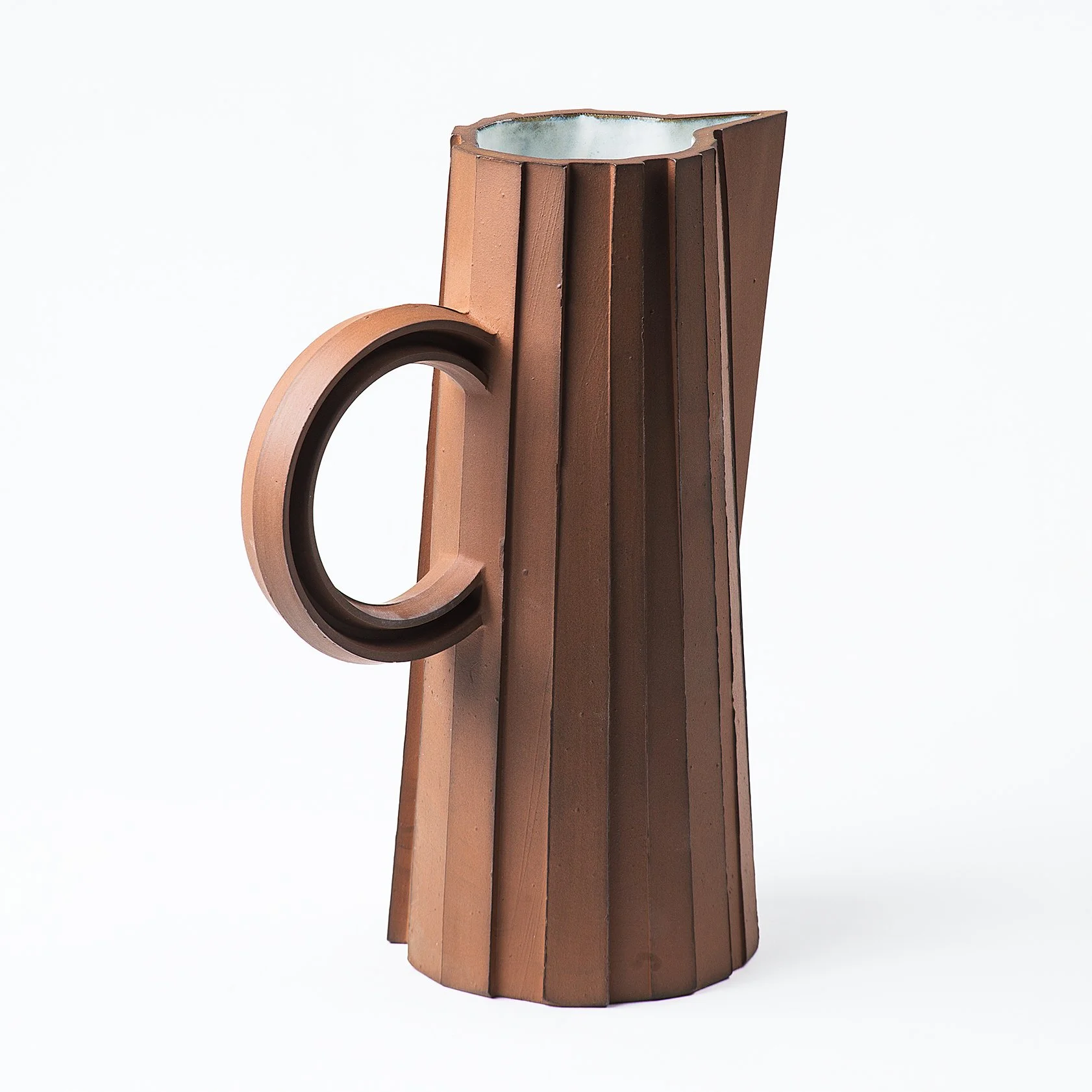 Handmade faceted ceramic pitcher with unglazed red stoneware exterior and off-white glazed interior, by Lea & Nicolas