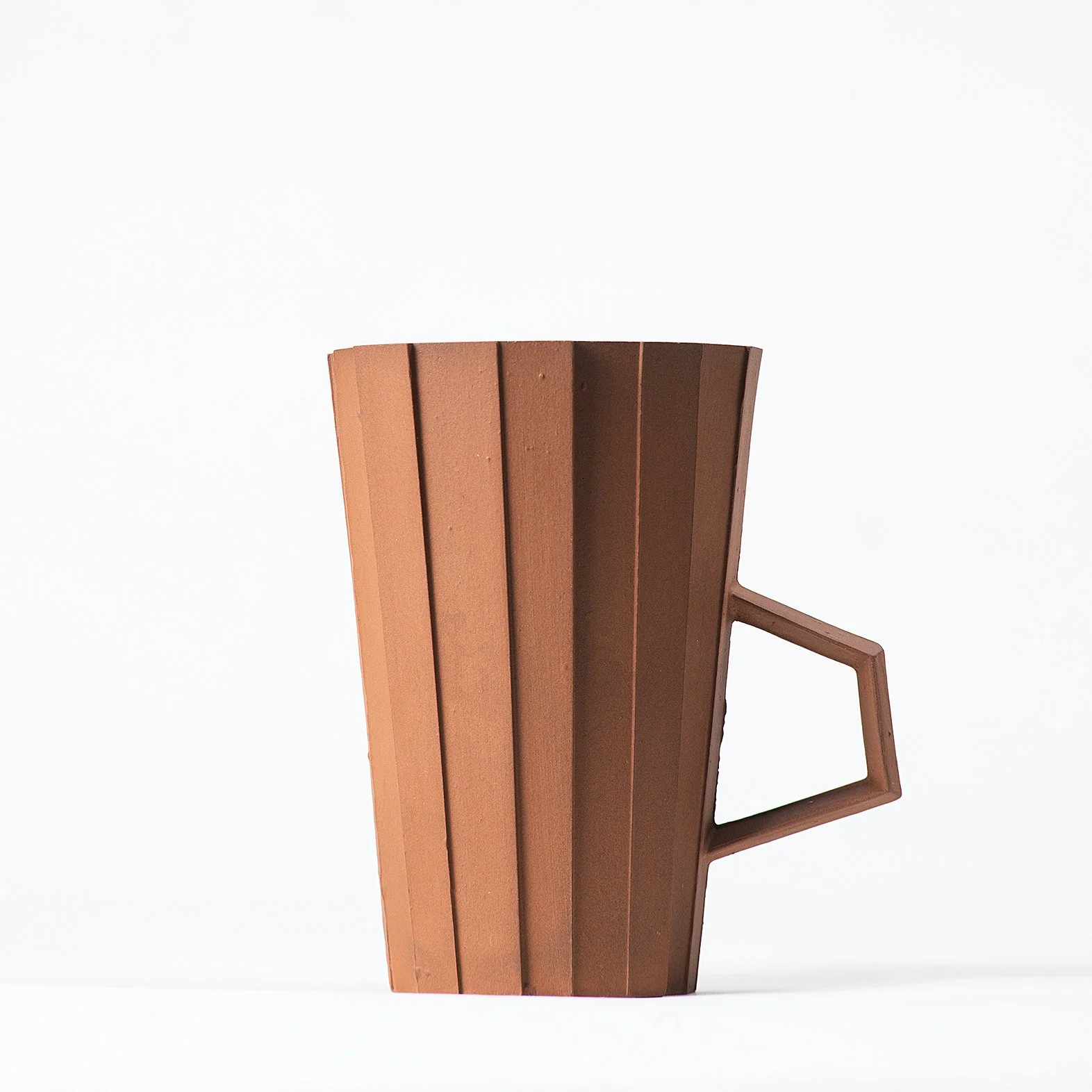Handmade faceted ceramic cup with unglazed red stoneware exterior and off-white glazed interior, by Lea & Nicolas
