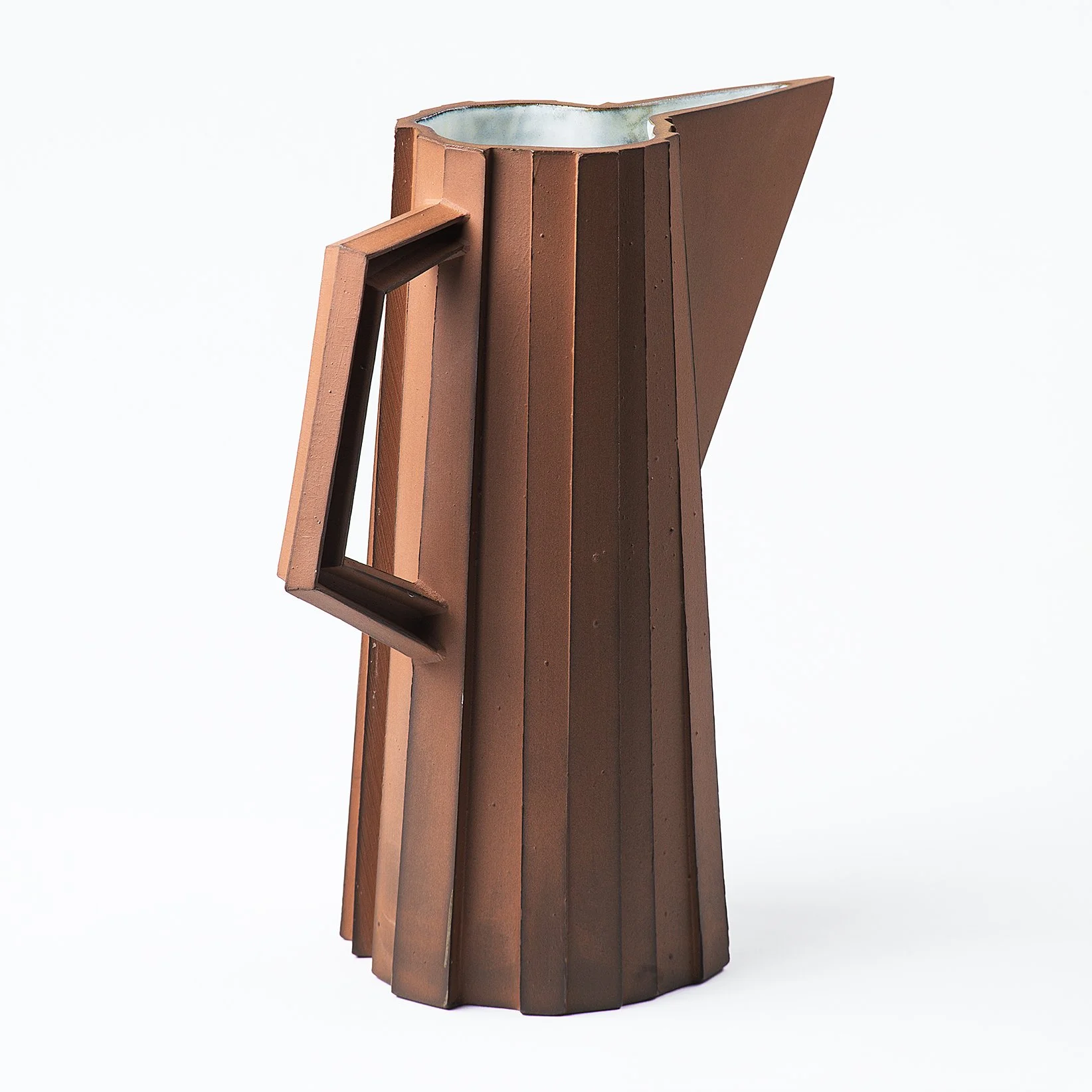 Handmade faceted ceramic pitcher with unglazed red stoneware exterior and off-white glazed interior, by Lea & Nicolas