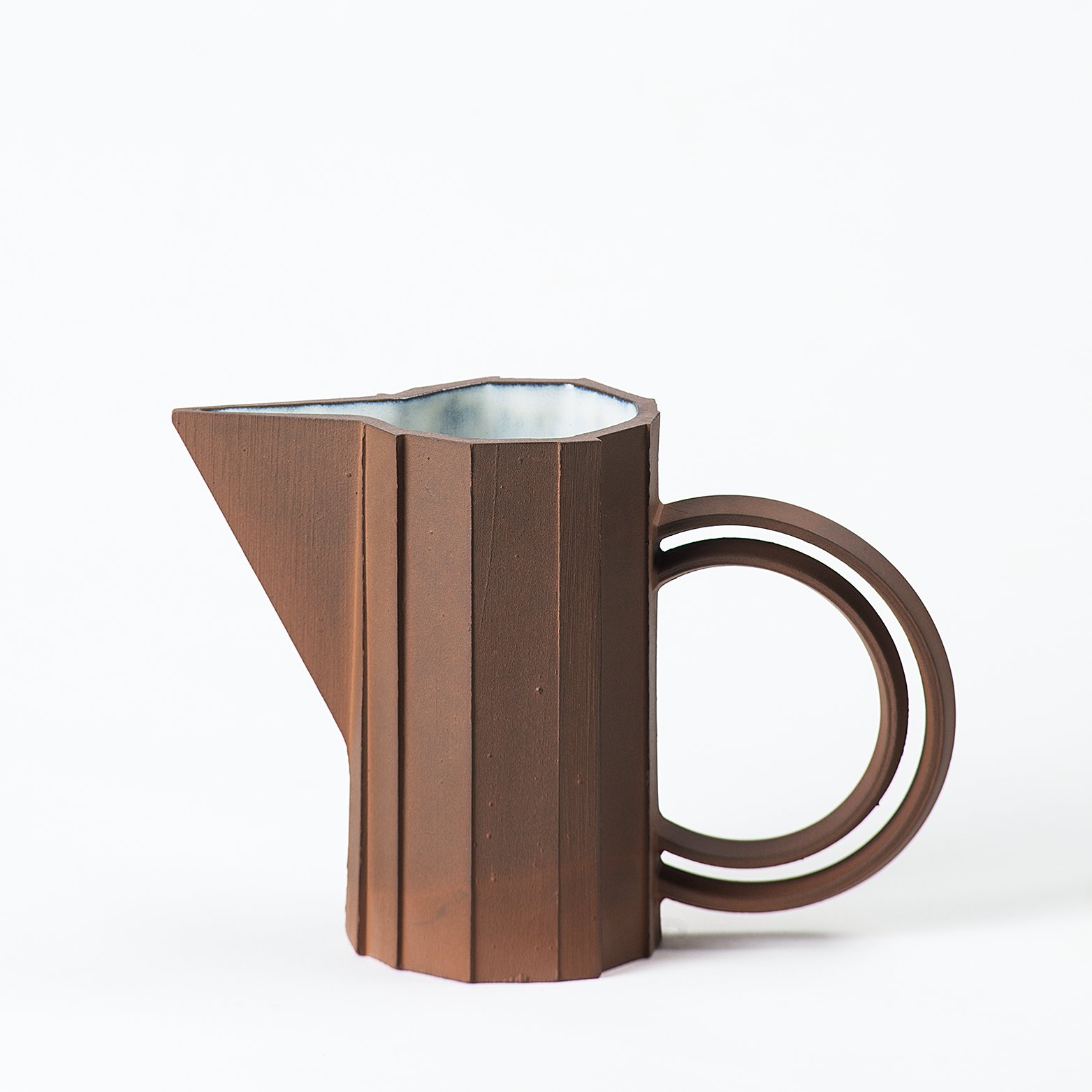 Handmade faceted ceramic pitcher with unglazed red stoneware exterior and off-white glazed interior, by Lea & Nicolas