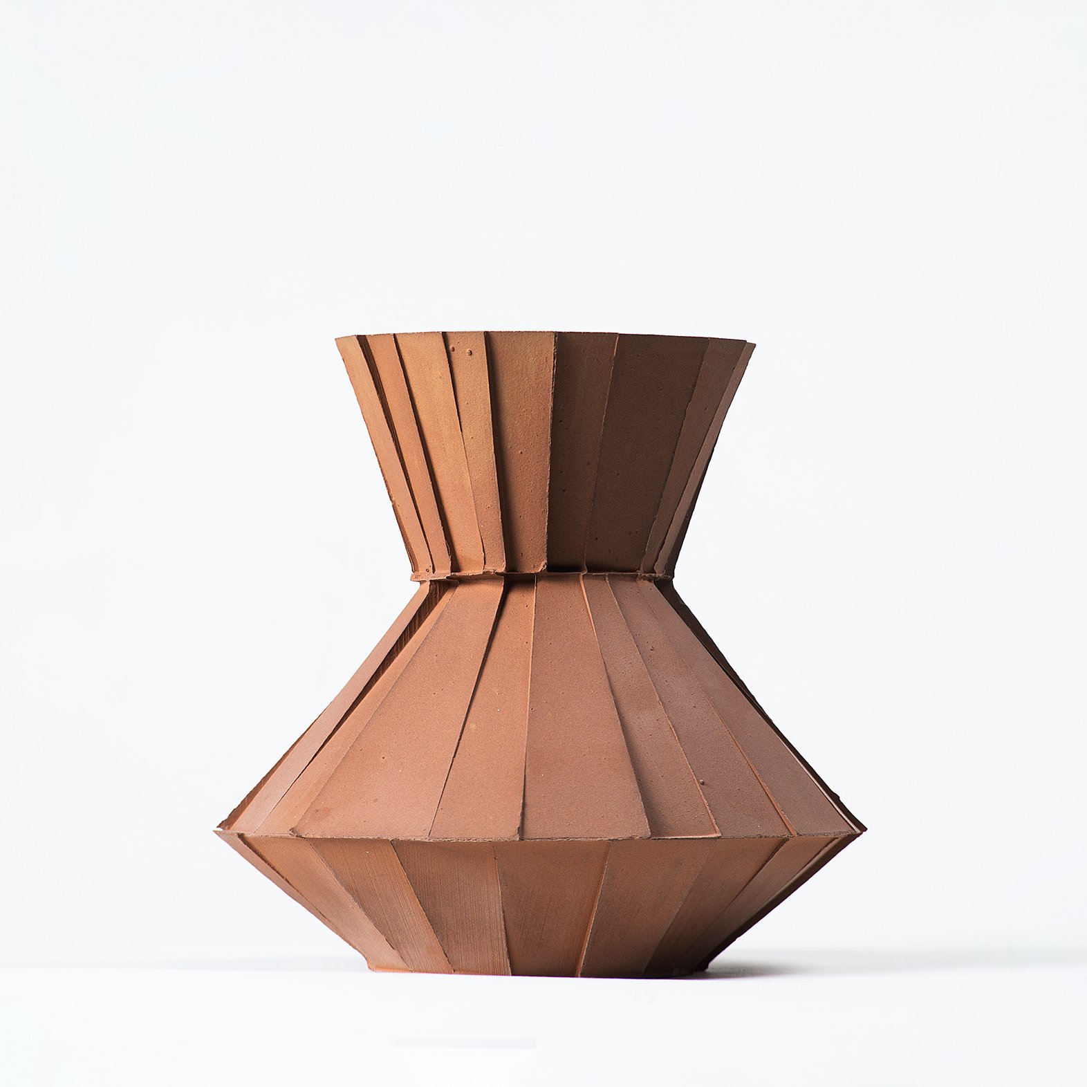 Handmade faceted ceramic carafe with unglazed red stoneware exterior and off-white glazed interior, by Lea & Nicolas