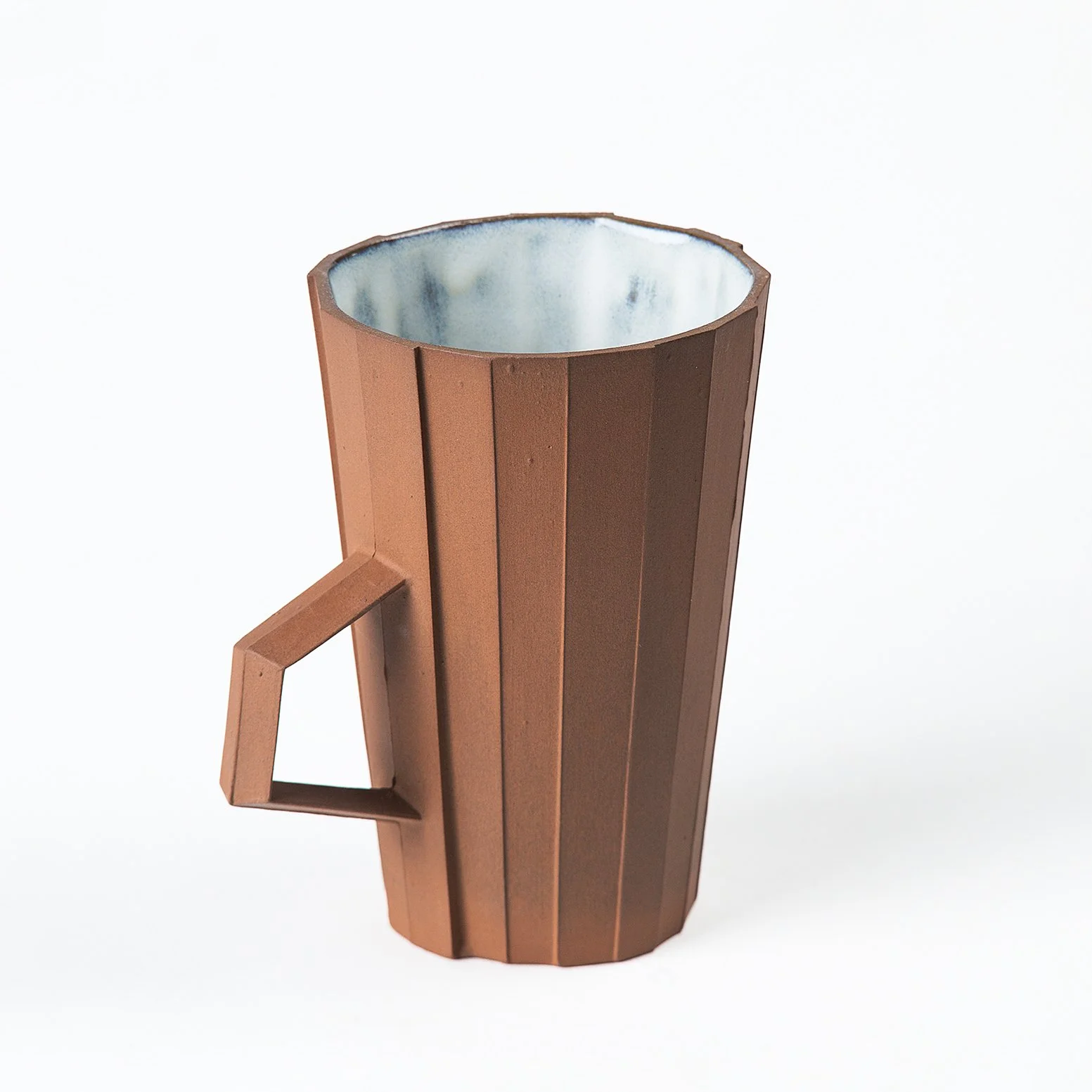 Brutalist handmade faceted ceramic cup with unglazed red stoneware exterior and off-white glazed interior, by Lea & Nicolas