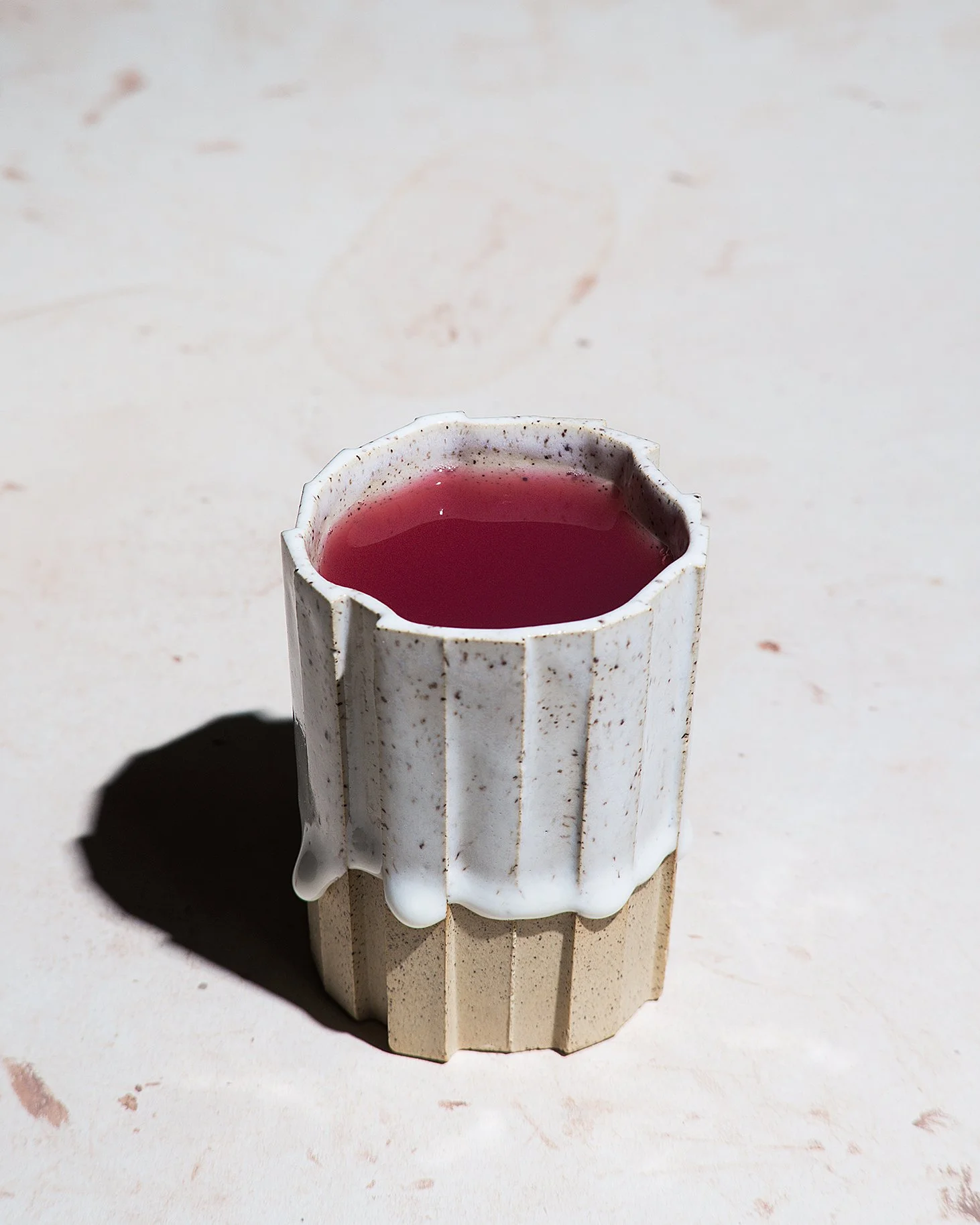 Handmade brutalist faceted ceramic tumbler, speckled white stoneware and drippy glaze, by Lea & Nicolas