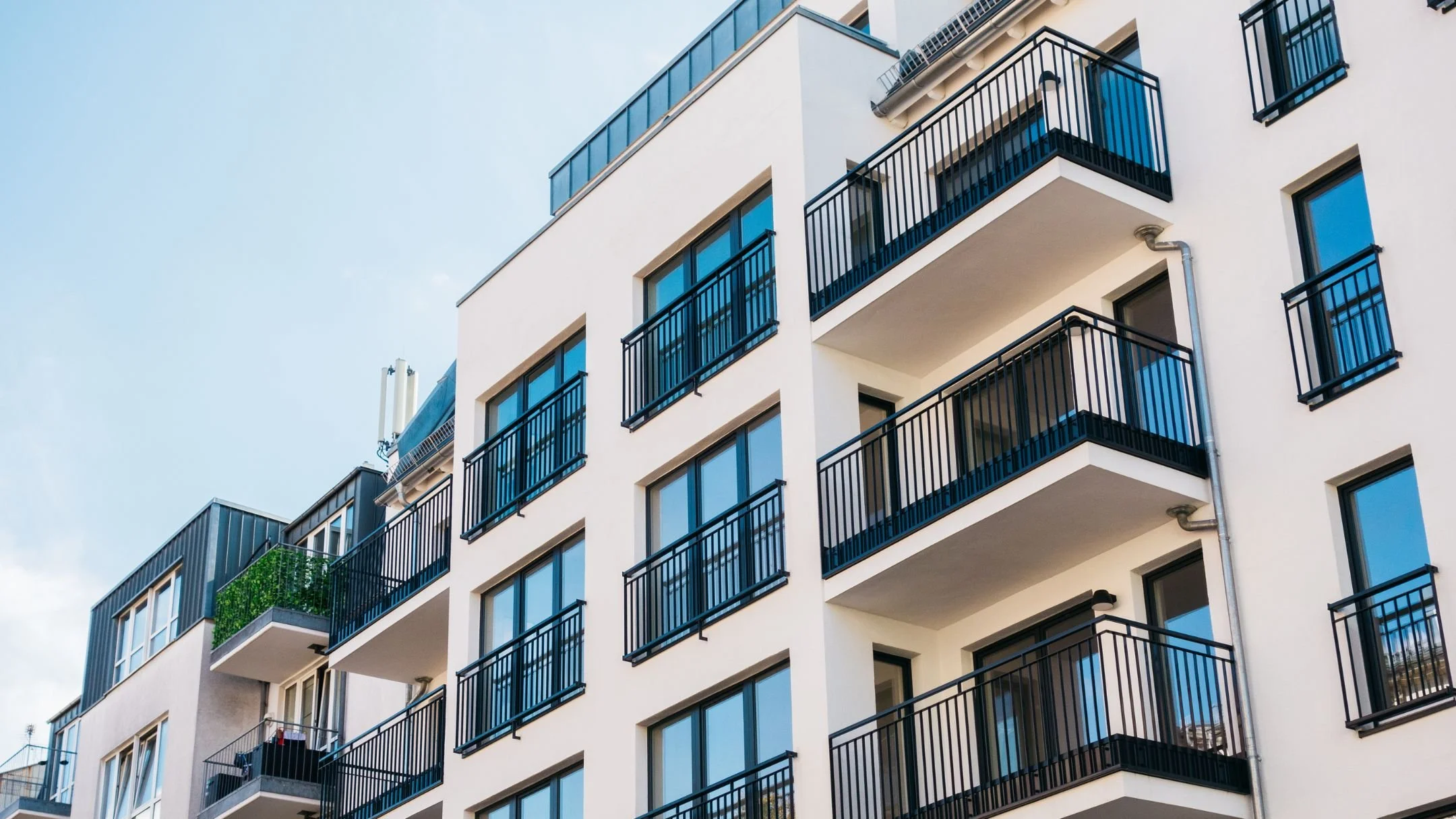 Zu sehen ist ein modernes Mehrfamilienhaus mit Balkonen und großen Fensterflächen als Beispiel für energetische Sanierungsmaßnahmen im Wohngebäudebereich.