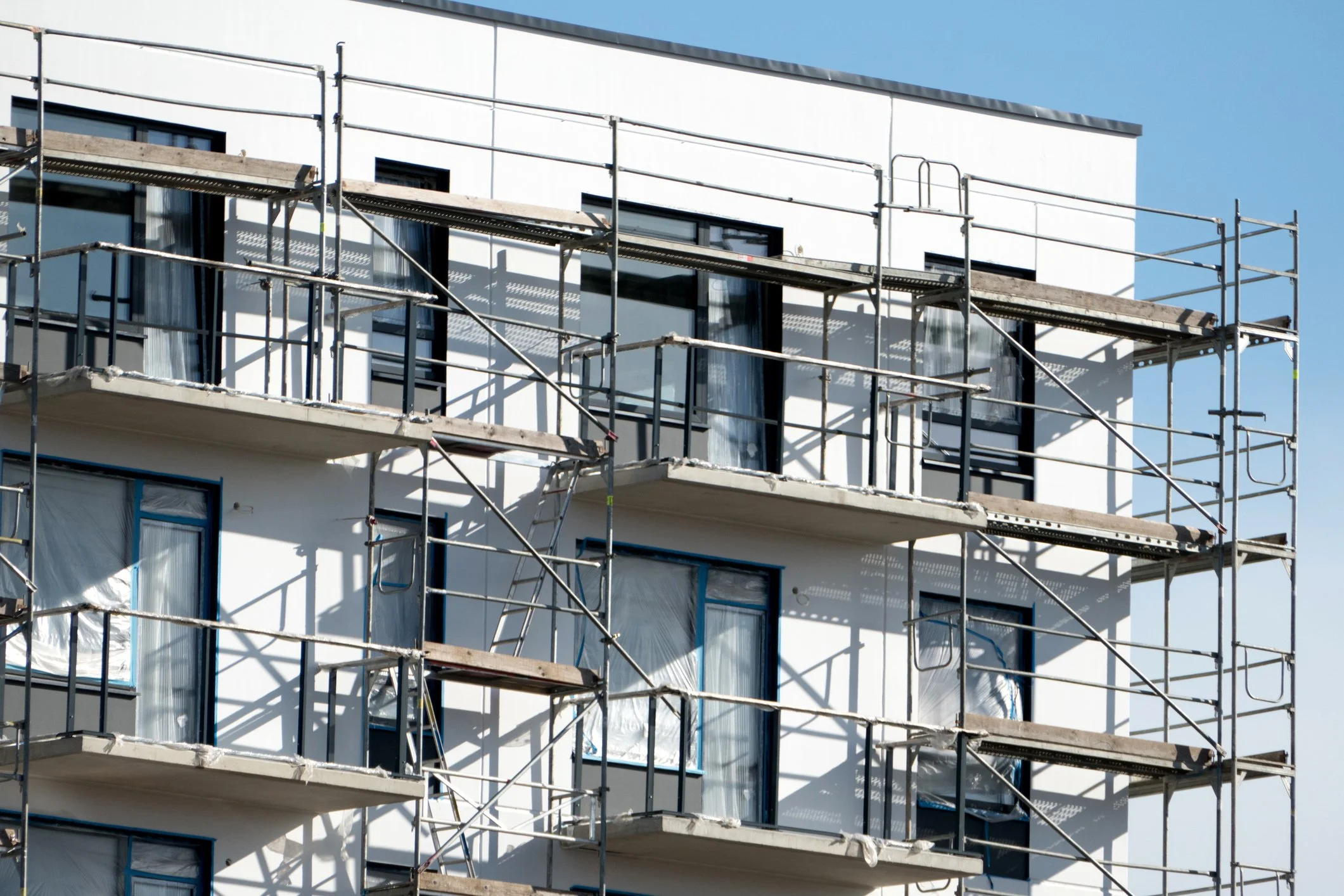 Detailansicht einer modernen Gebäudefassade mit Gerüst aufgrund von Sanierungsarbeiten.