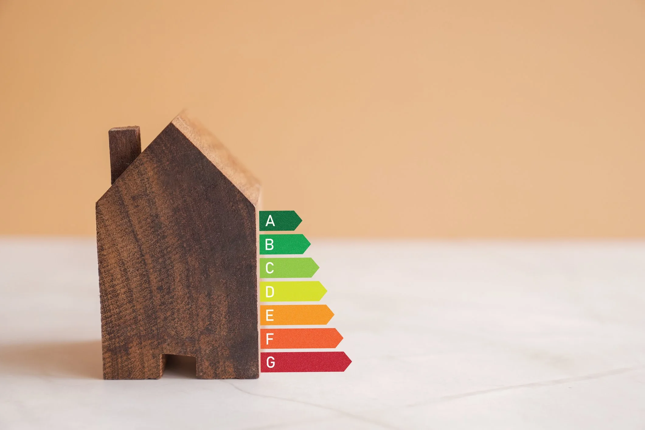 Modell eines Gebäudes aus Holz mit einer Darstellung der Energieeffzienzklassen daneben.