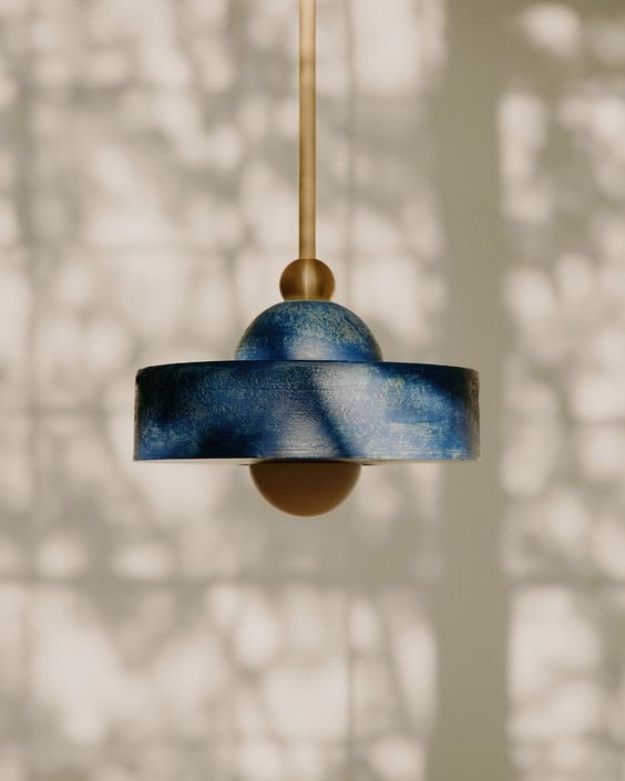 Modern blue and gold pendant light with shadow patterns on wall