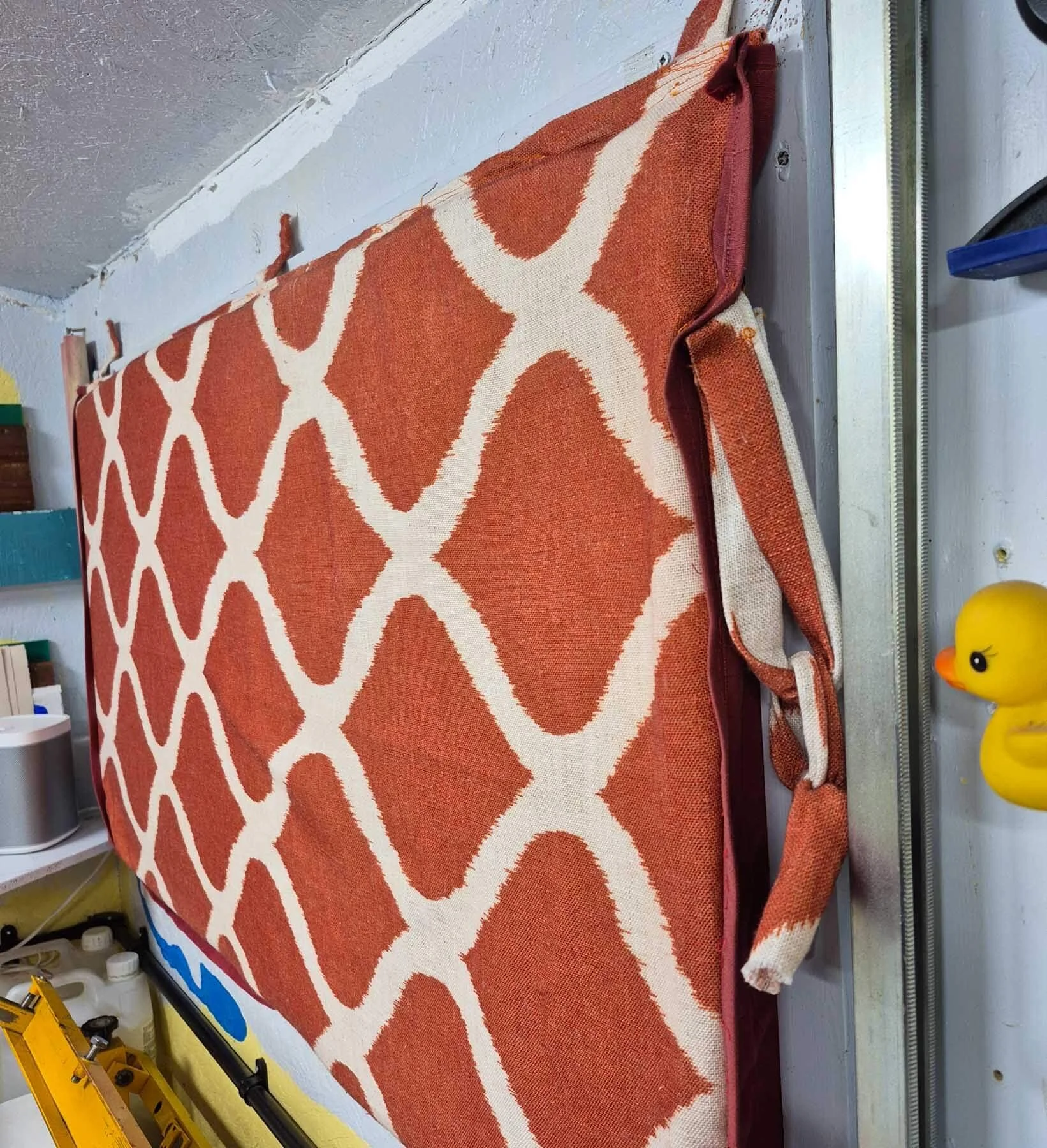 A handmade padded window panel with patterned fabric and foam inside, used to insulate a studio window.
