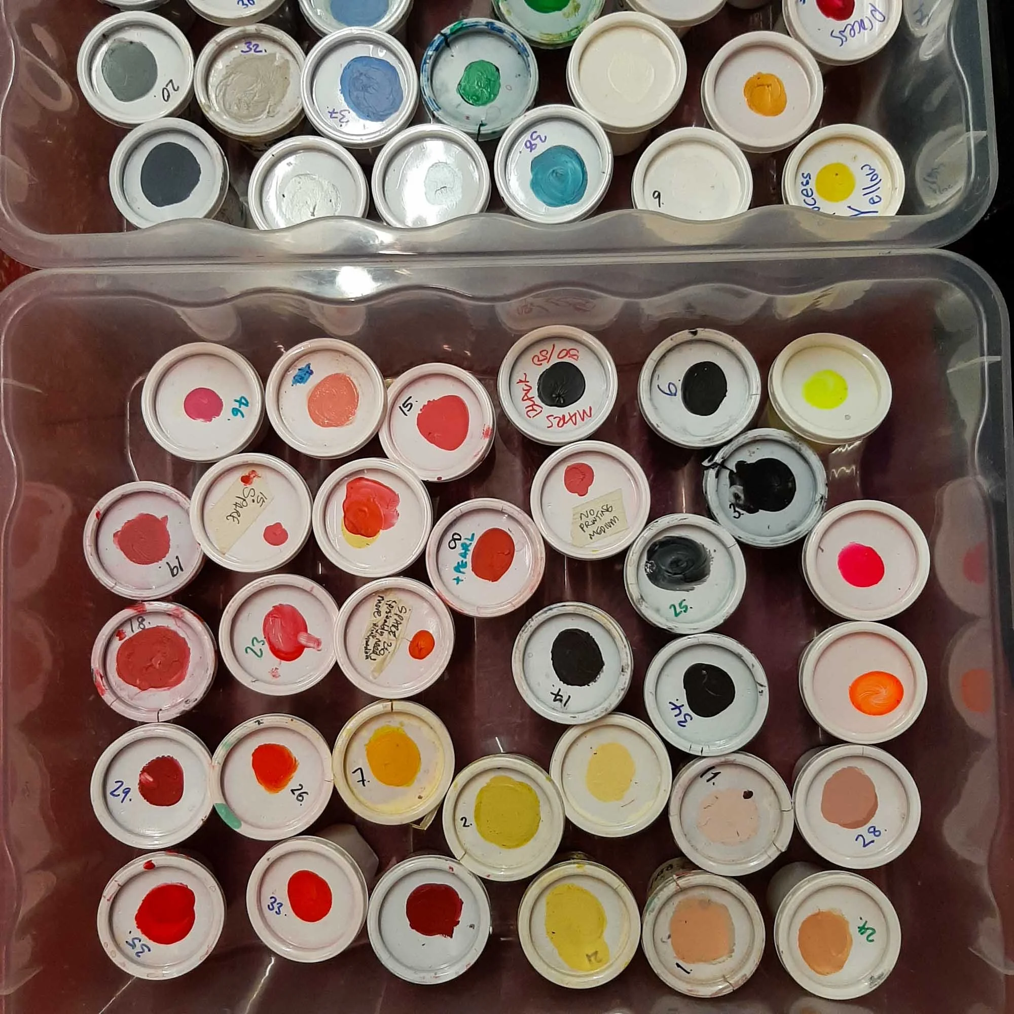 Assorted ink containers with colour‑coded lids viewed from above, used for storing mixed inks.