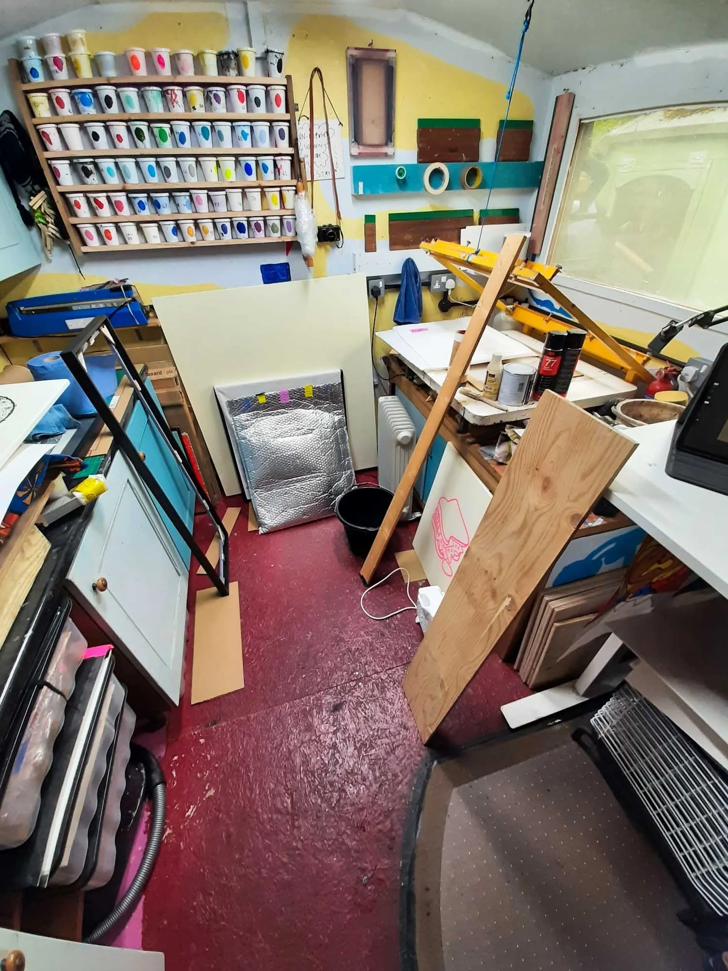 Creative silkscreen studio filled with tools, materials, and colour-coded supplies, showcasing a vibrant and hands-on workspace.