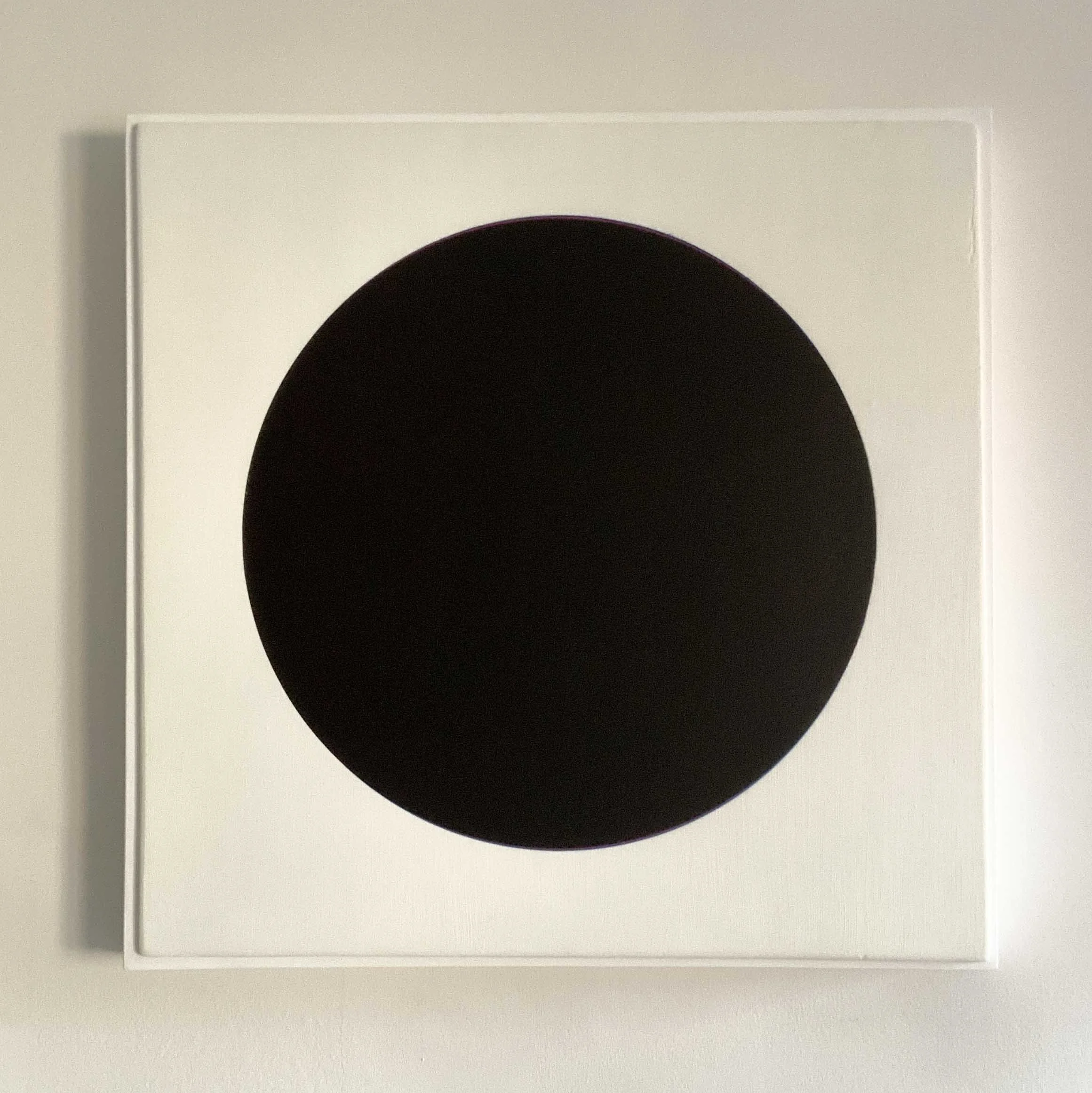 Minimalist art piece with a large black circle on a white background