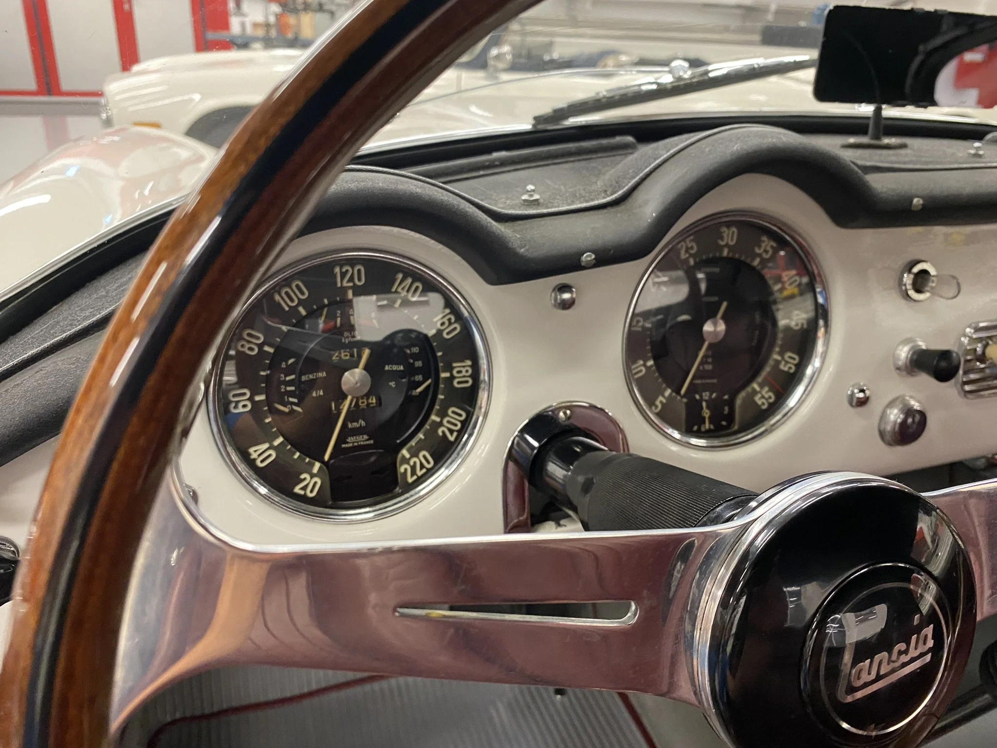 Innenraum eines klassischen Lancia-Automobils, Fokus auf Tachometer und Lenkrad.