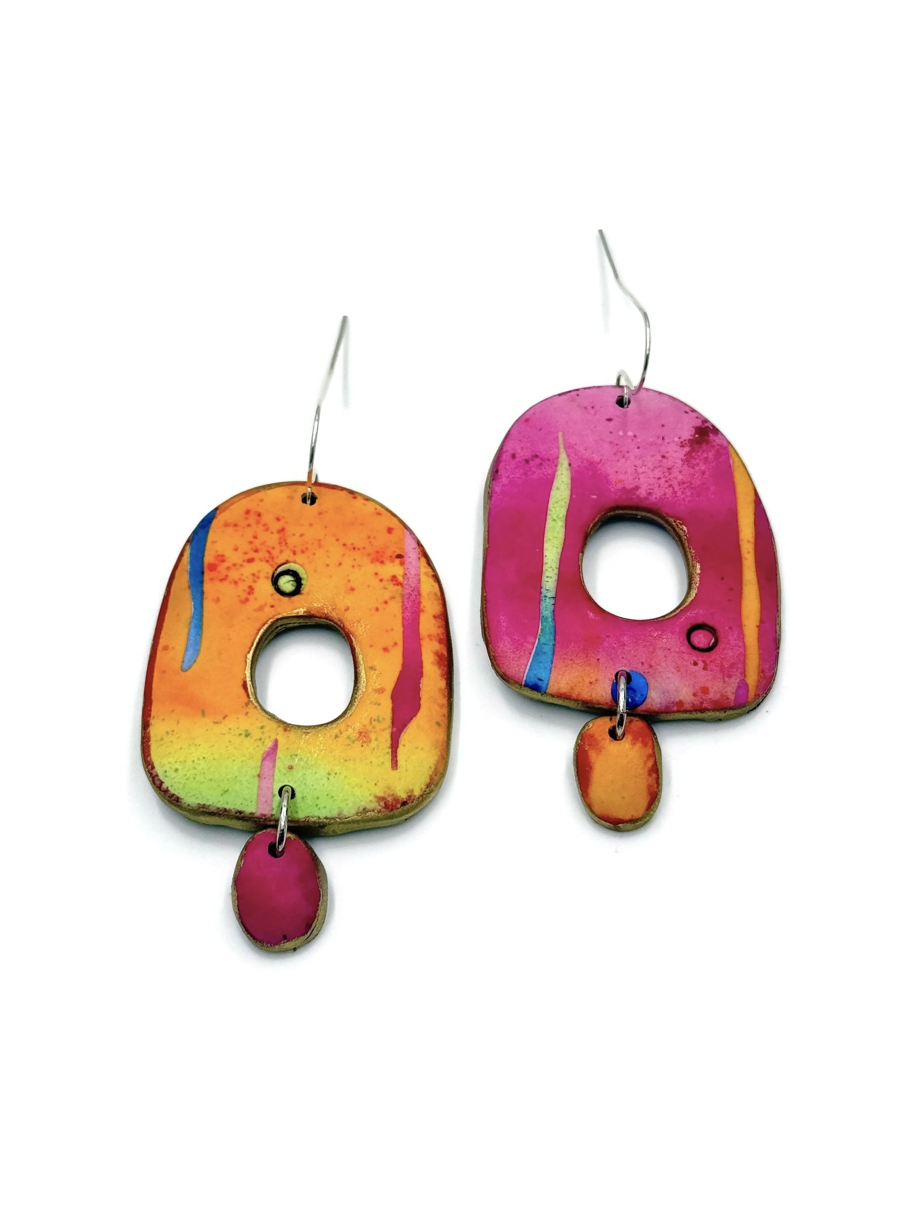 Mismatched polymer clay earrings in sunset pink, orange and yellow tones with cut-out shapes and dangling drops