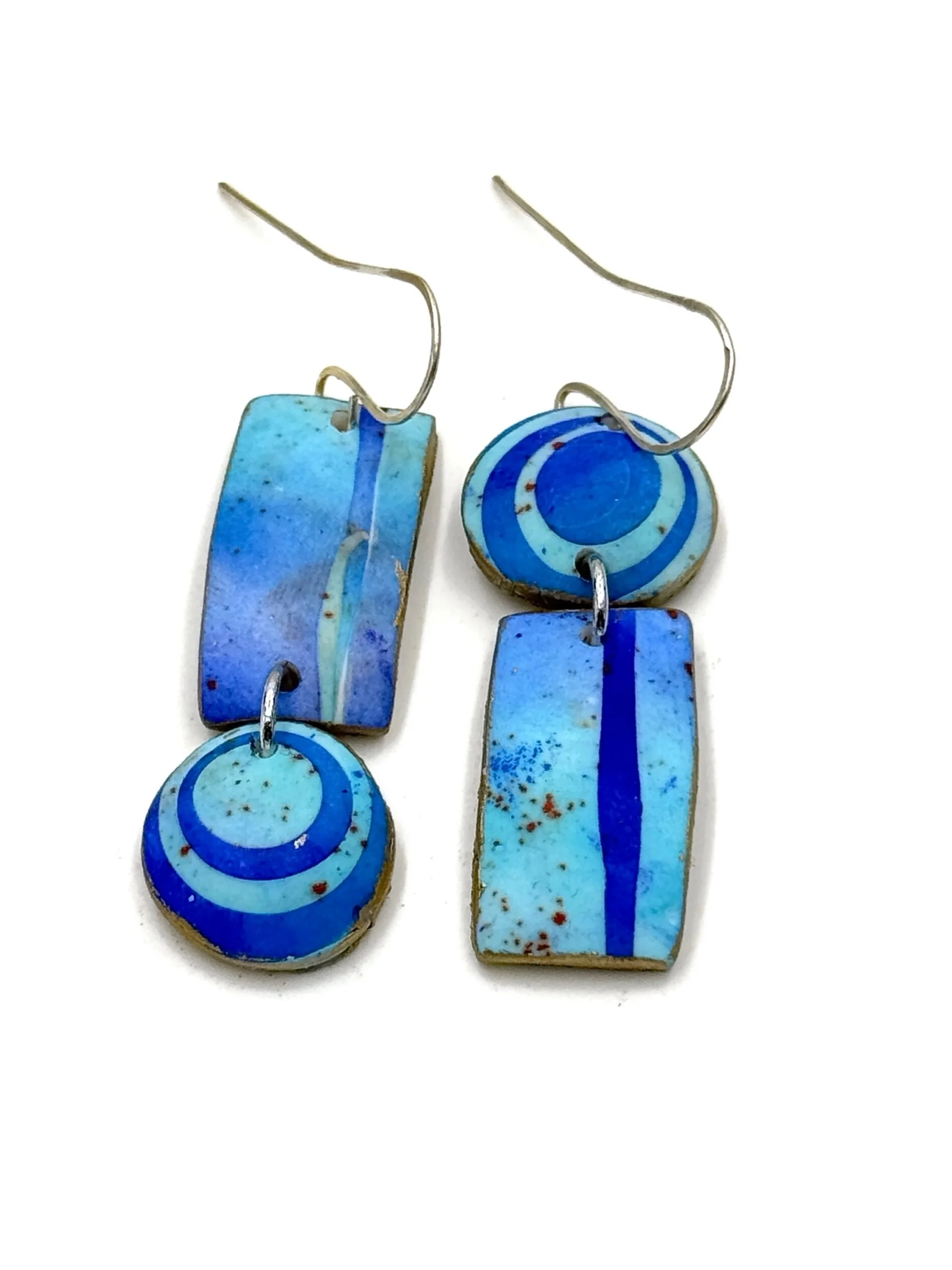 Handmade geometric drop earrings in layered blue tones featuring circular and rectangular shapes with graphic patterns and painterly textures.