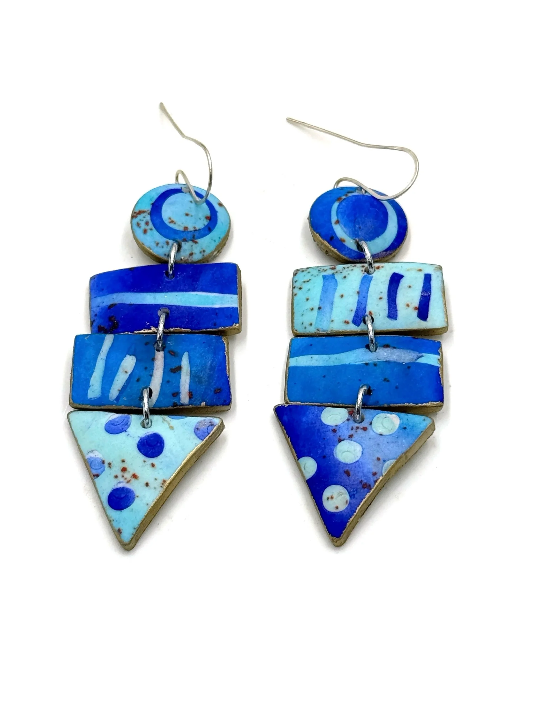 Handmade statement earrings in layered blue tones featuring geometric shapes, graphic patterns, and shoreline-inspired details.