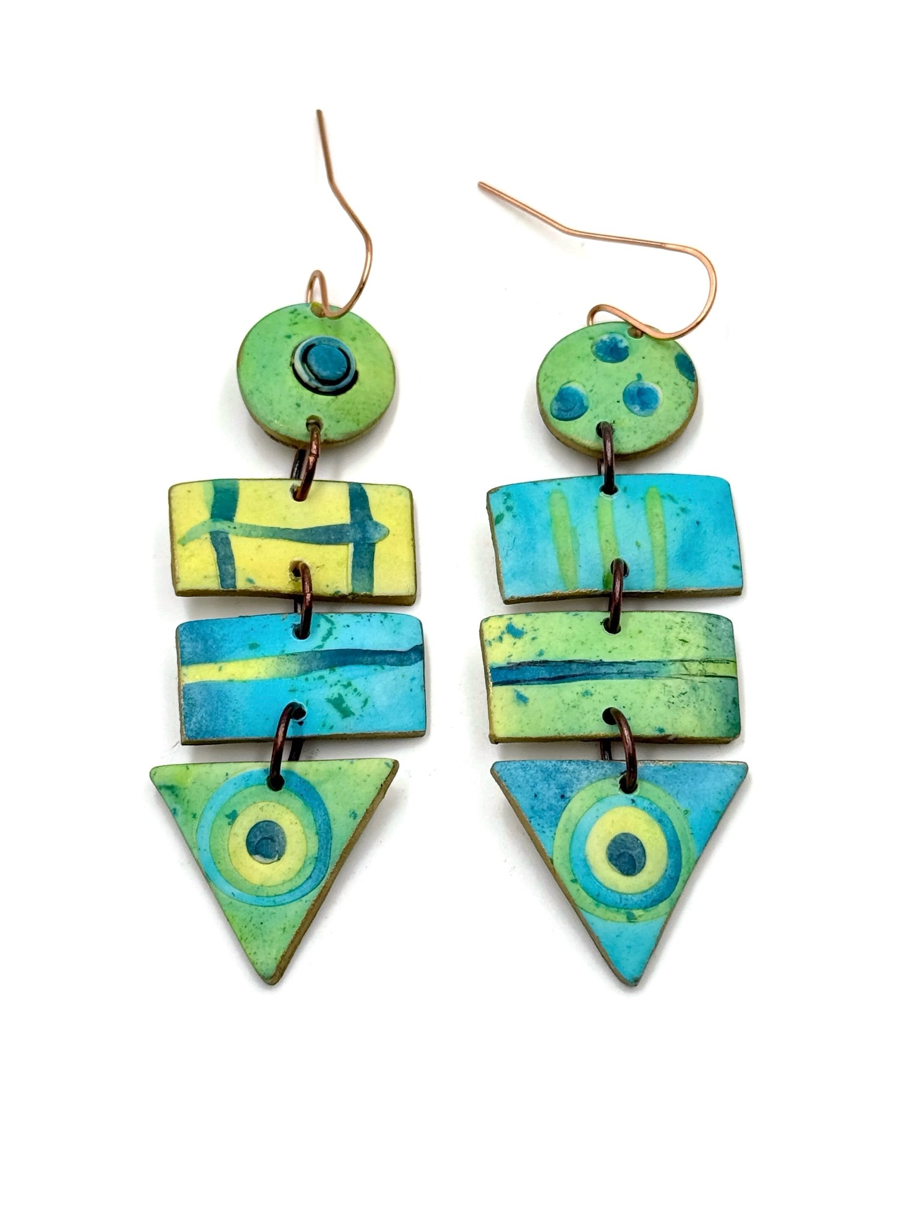 Handmade geometric statement earrings in green, turquoise, and blue with circular, rectangular, and triangular shapes and copper ear wires.