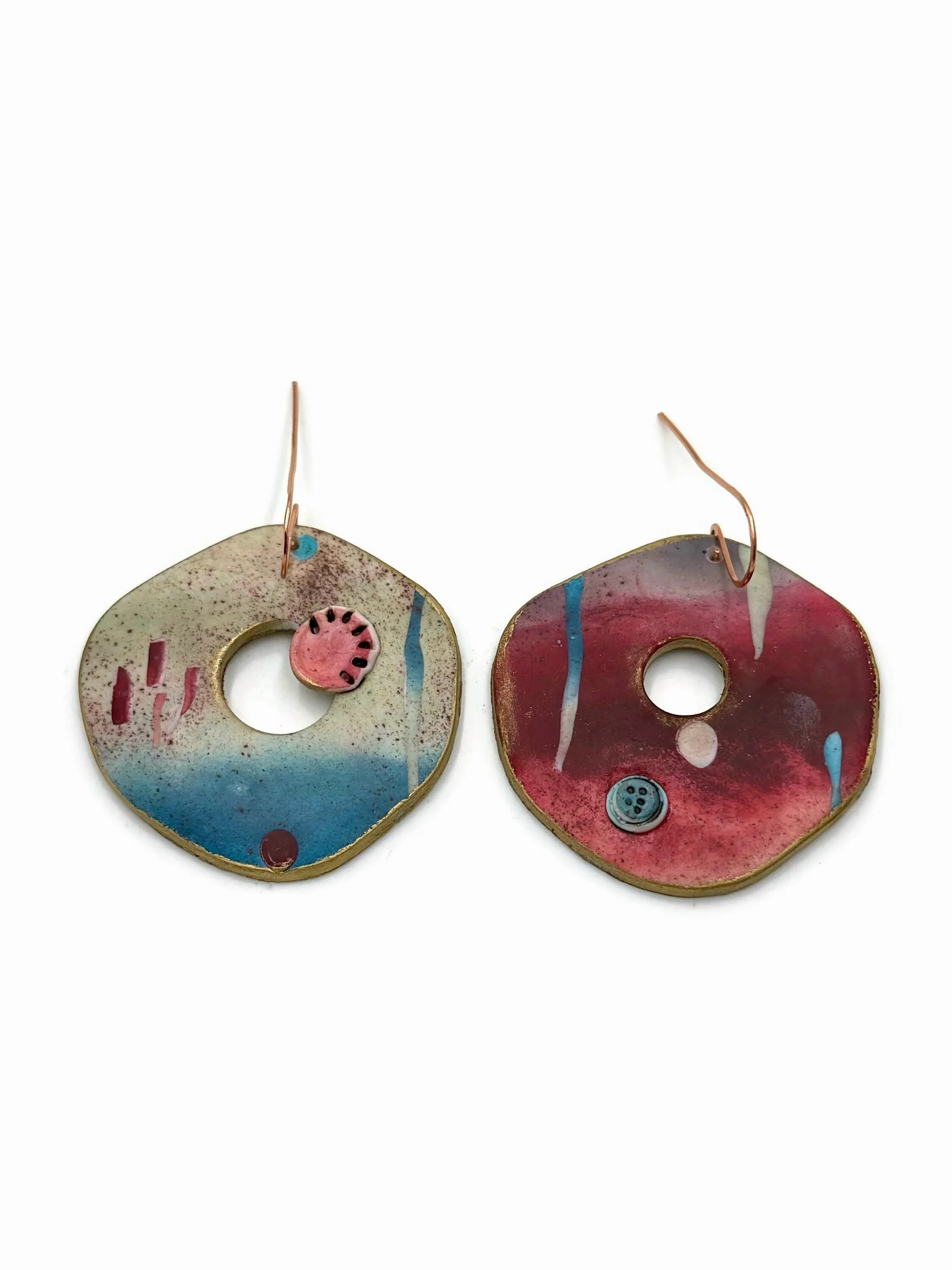 Handmade abstract statement earrings with circular cut-outs in cream, turquoise blue, muted red, and dusty pink tones with copper ear wires.