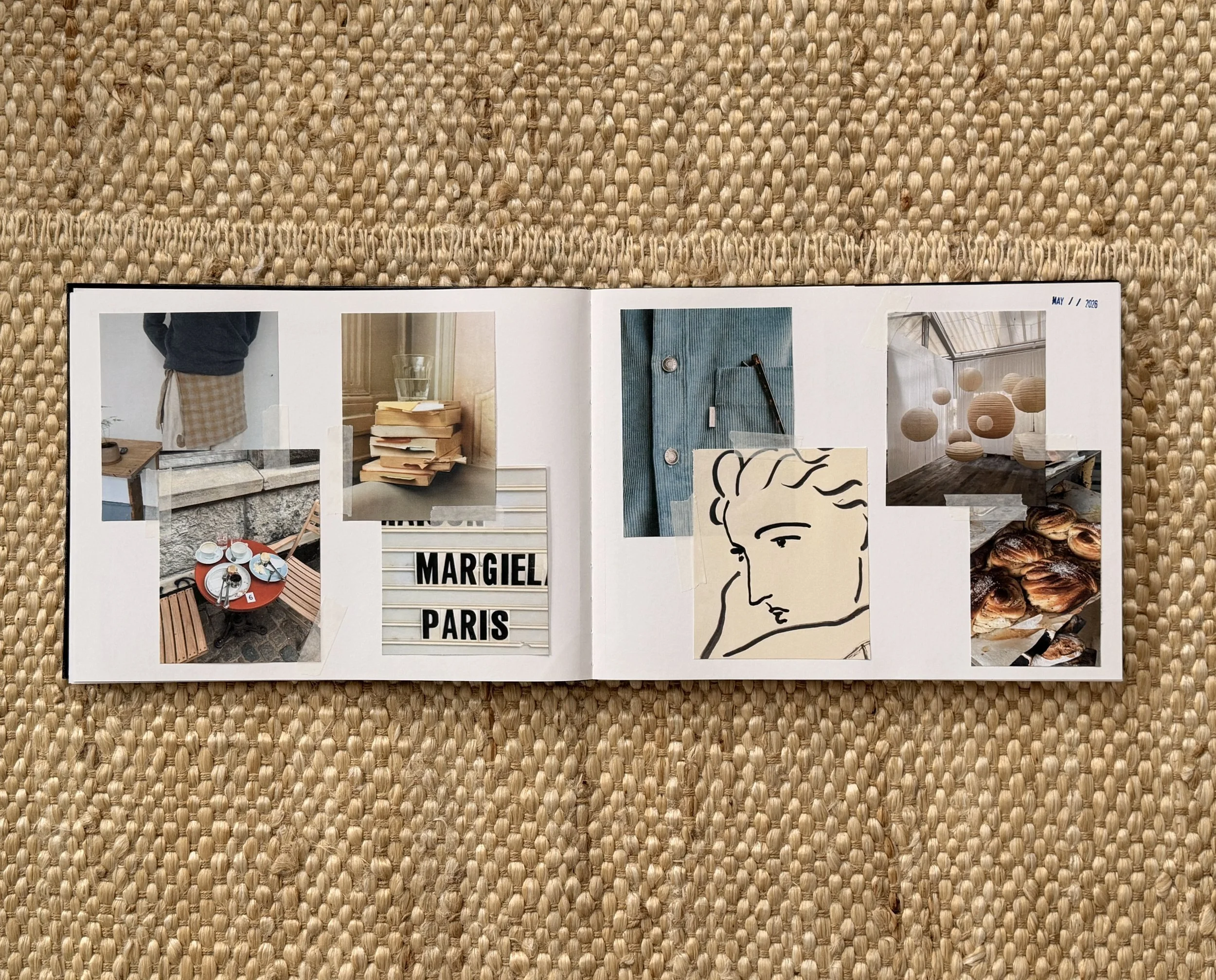 Open magazine or photo album on a woven straw surface. The visible pages show various images and text, including a person in a blue sweater and checkered apron, a stack of books, a glass of water, and abstract art. The top right corner indicates the date May 11, 2026.