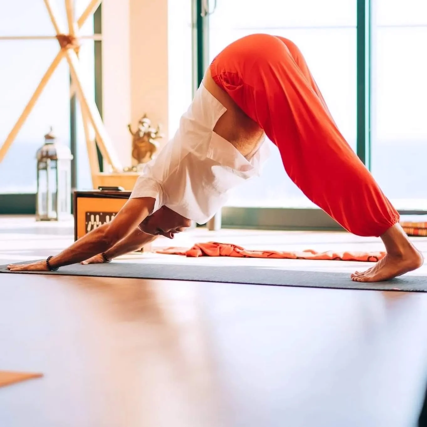 Person practicing yoga in a downward dog pose inside a bright room.