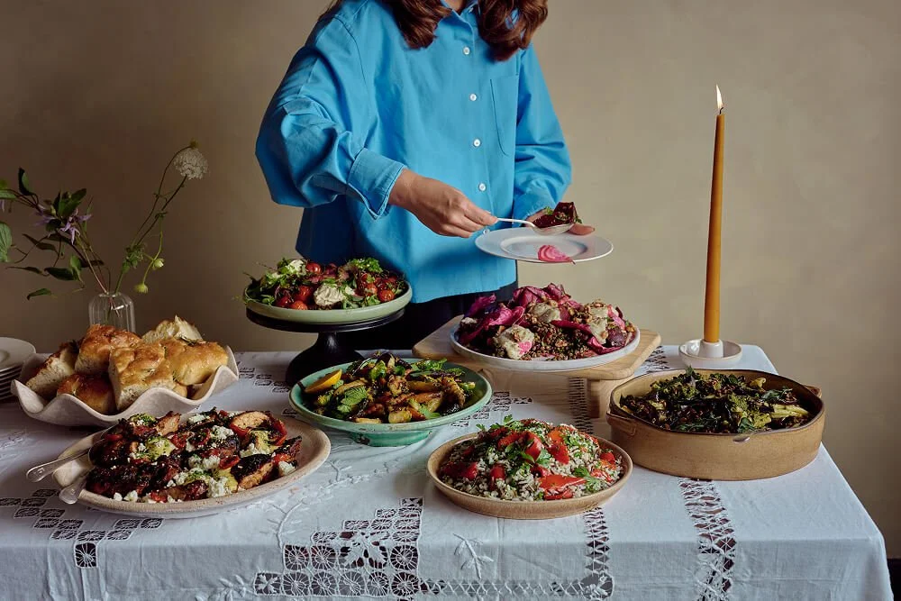 Someone serving themselves a plate of food from a full Christmas buffet table