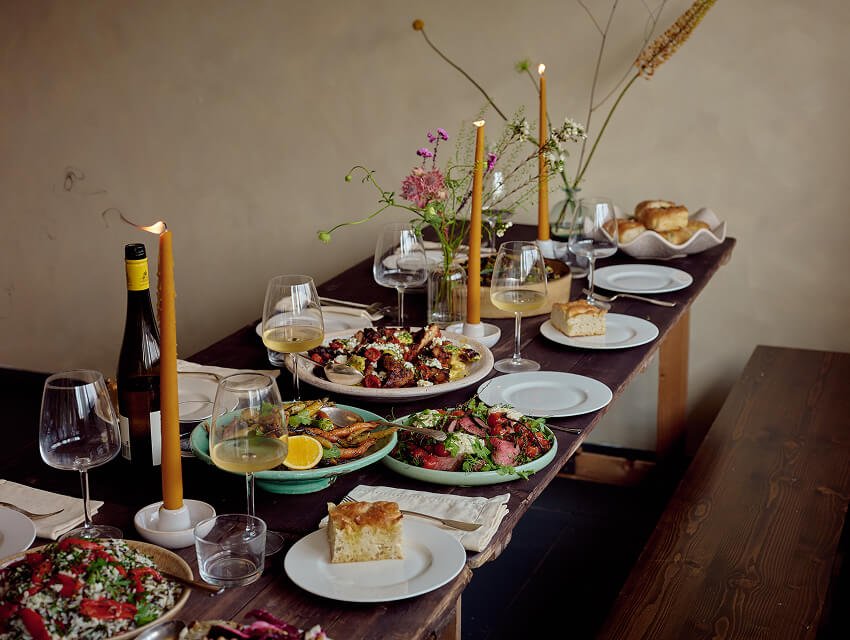 A beautifully layed supper club table in the grace and skye studios with platters of food and wine spread for a feast for ten.