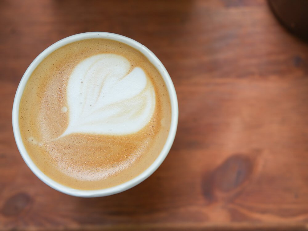 An image of a barista flat white on the top of Grace & Skye's wooden coffee bar