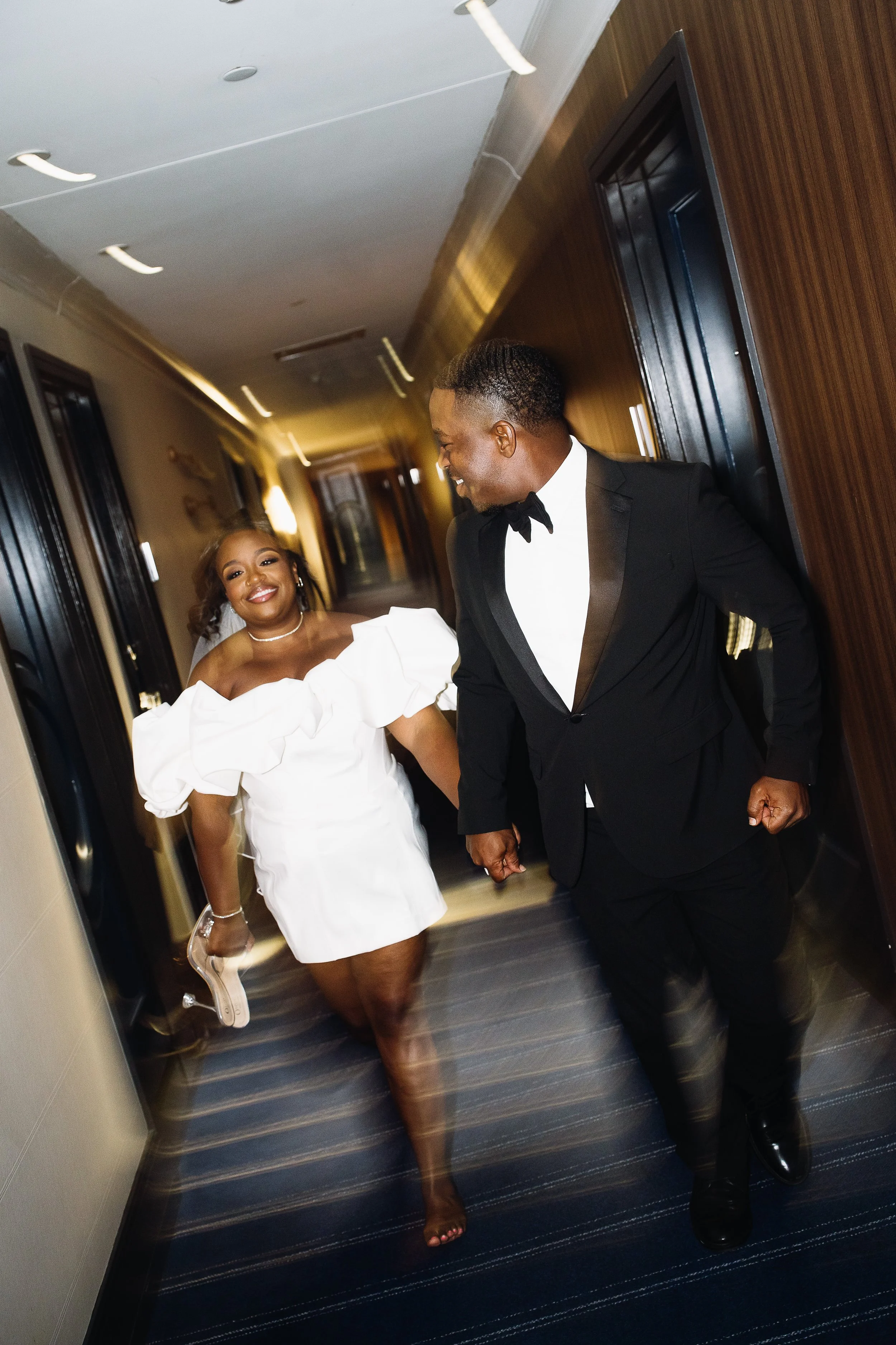 Black couple racing down at the Kimpton hotel in Winston Salem, NC hallway with motion blur.