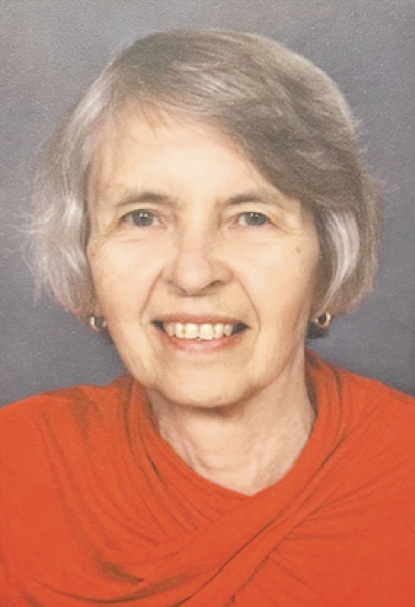 Photograph of an older woman with short gray hair, smiling, wearing a red top and small hoop earrings.