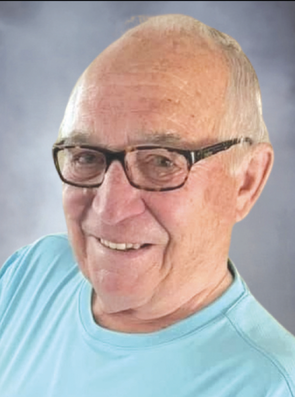 Smiling elderly man with glasses and a turquoise shirt against a gray background.