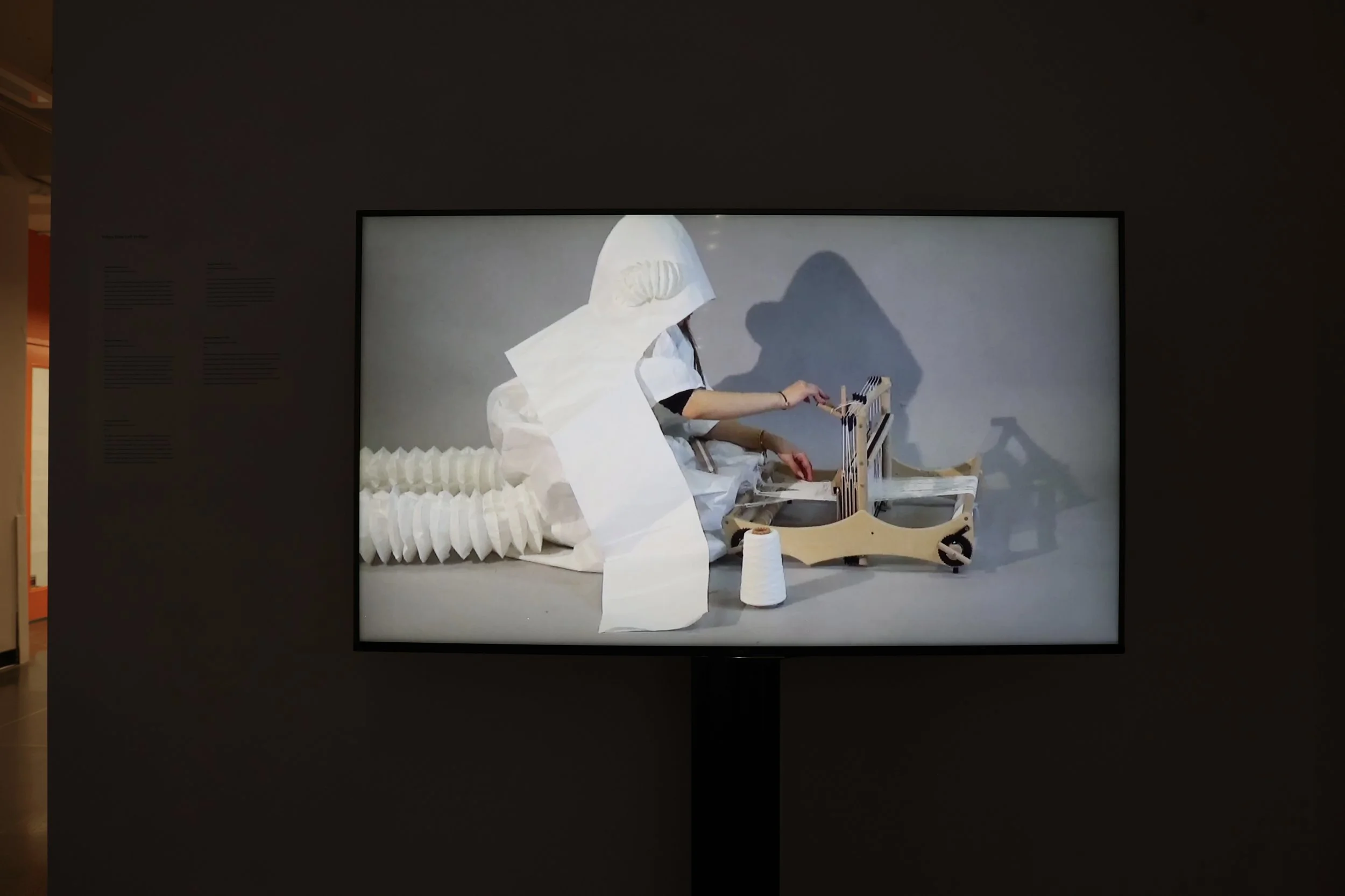 Installation view of the first studio performance shown on a monitor with a stand in the exhibition hallway. Photograph by Aritra Das, 2026.