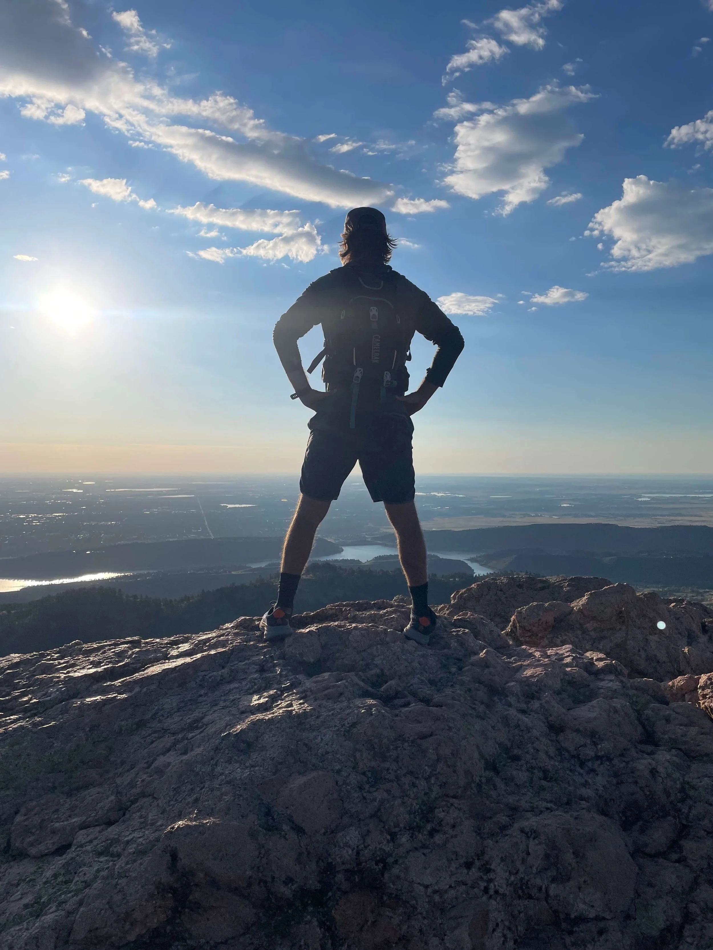 Jordan Bonifas standing on Horsetooth Rock above Fort Collins at sunrise