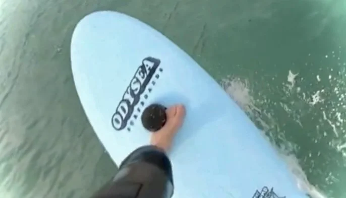 Person riding a paddleboard on the water, holding the paddle.