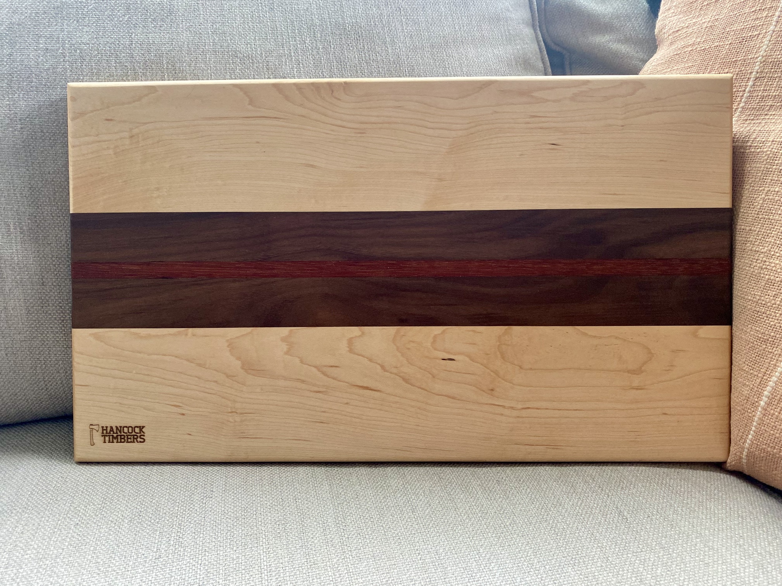 Crimson Line hardwood cutting board made from maple, walnut, and jatoba, featuring a bold red center stripe and smooth surface for chopping and everyday kitchen use.