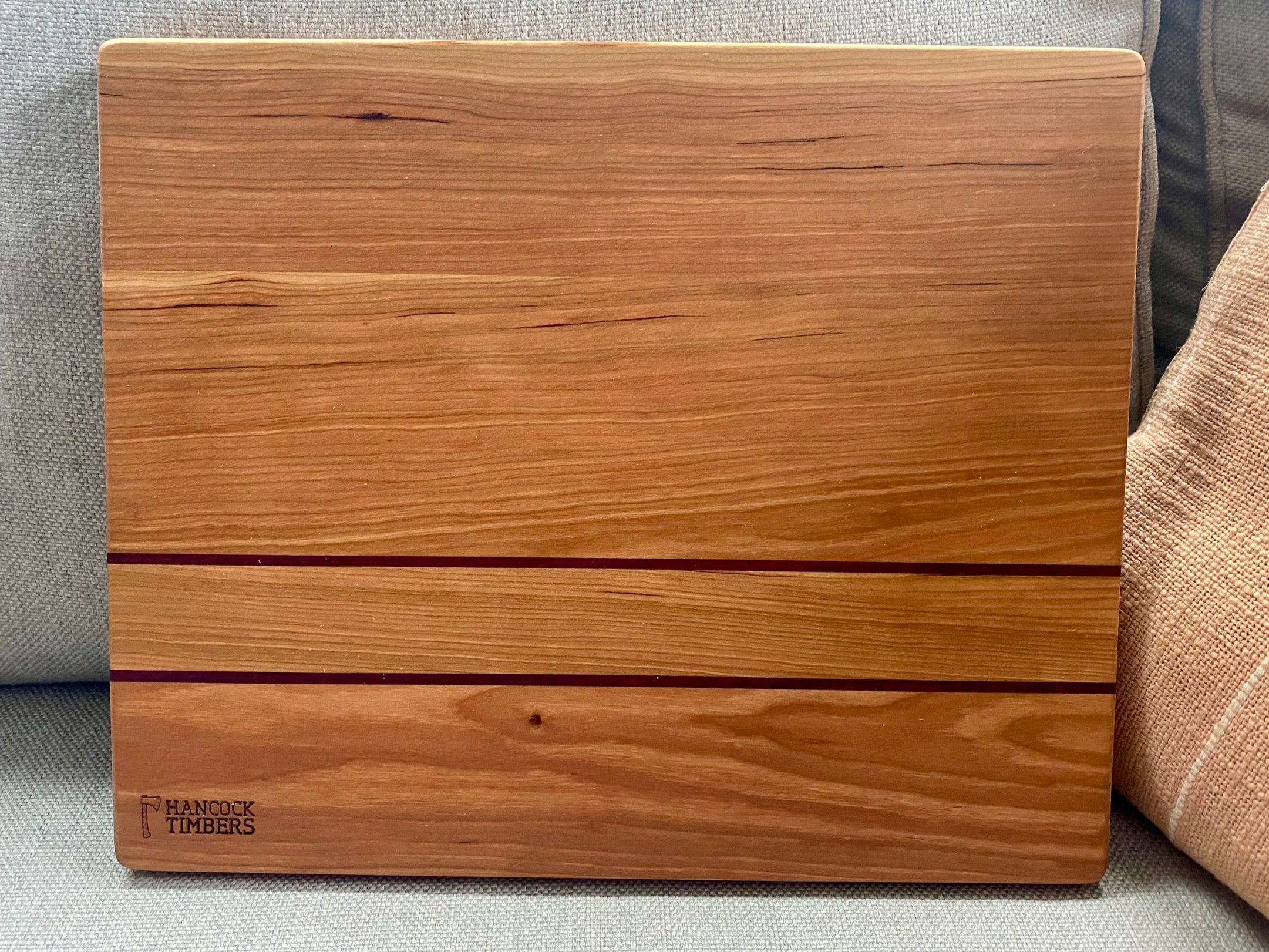 Solid cherry hardwood cutting board with contrasting accent stripe and smooth surface, designed for chopping, slicing, food prep, and everyday kitchen use.