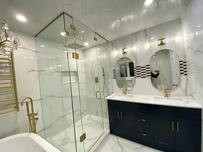 Stylish navy double vanity with quartz countertop, under-mounted sinks, and antique gold hardware in a luxury bathroom renovation in Bowmanville.