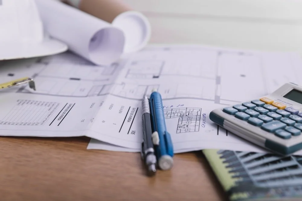 Close-up pens and calculator on plans