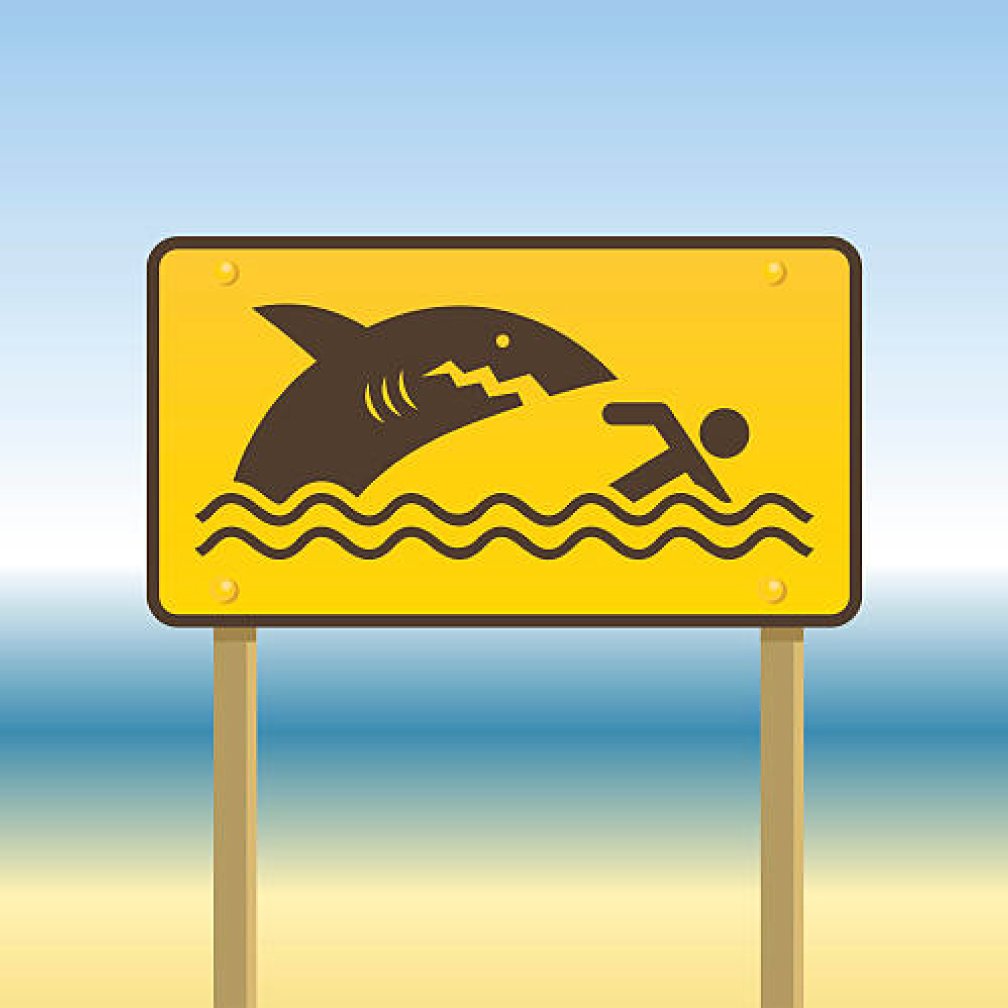 image of a safety sign showing a shark and a human in water.