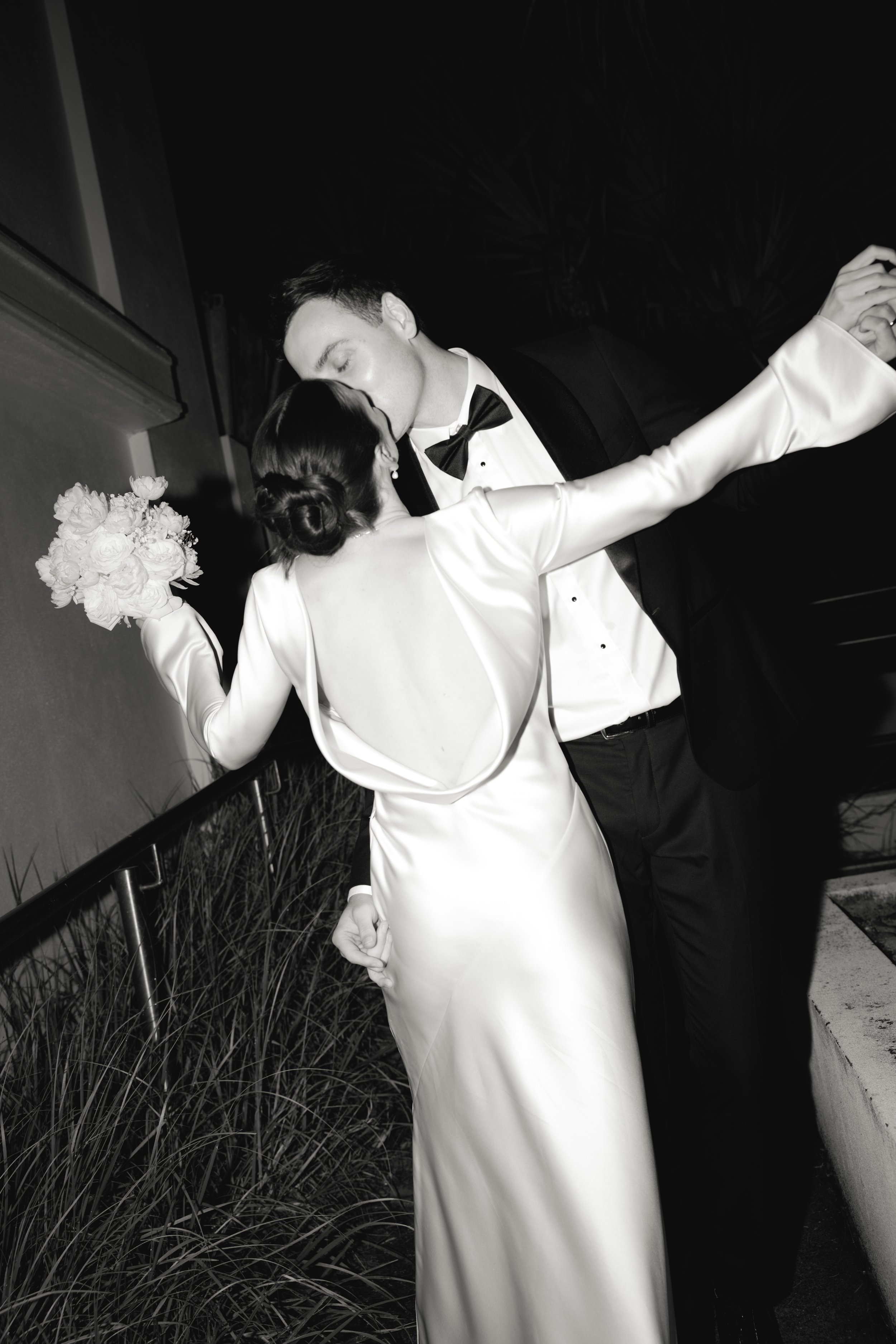 A black and white photo of a couple kissing. Wedding celebration captured at Rick Shores, in Burleigh Heads, Queensland